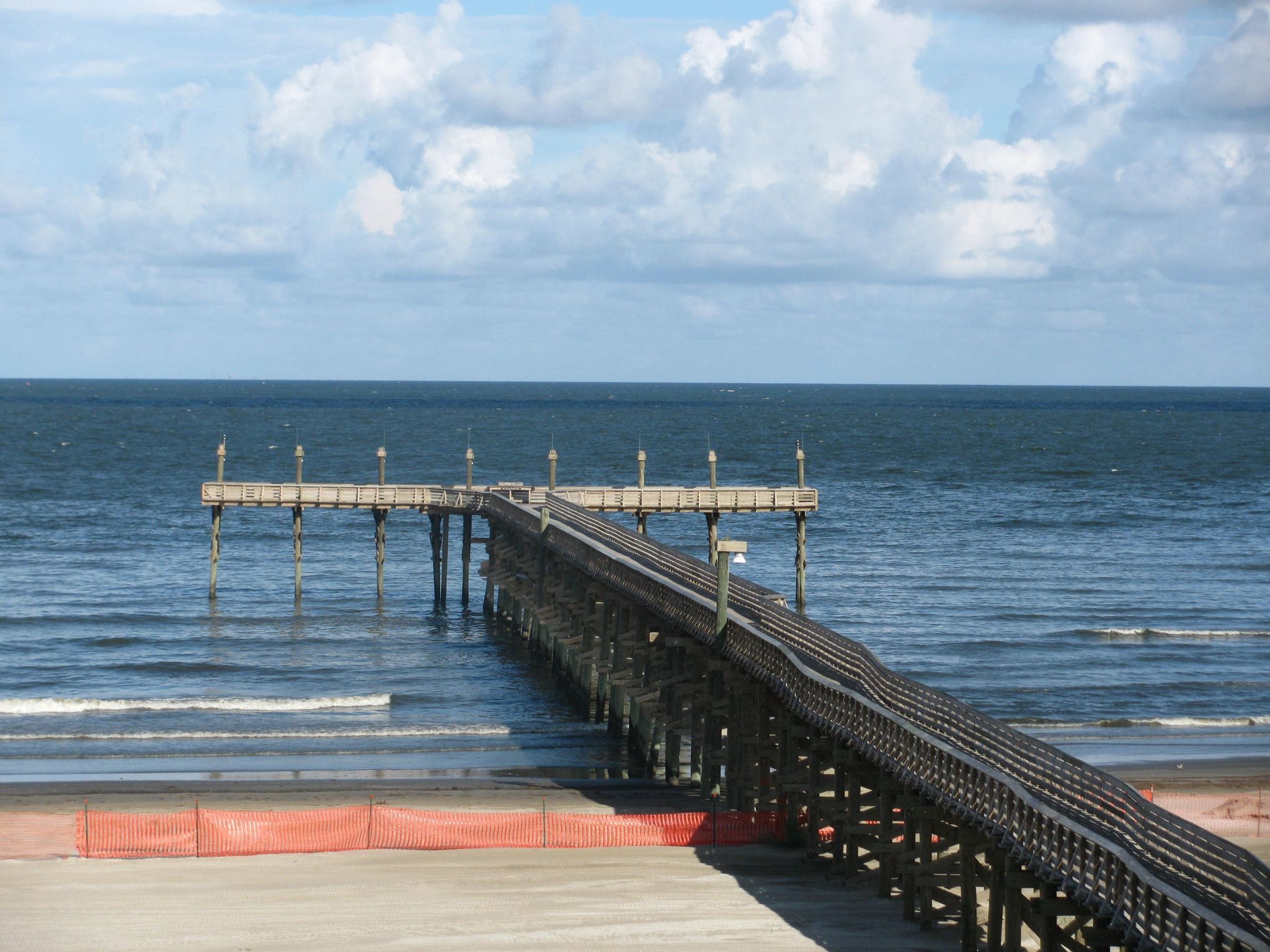 Wooden pier stretching into the ocean from a beach under a cloudy sky. - Fiddlers Loop Nature Trail