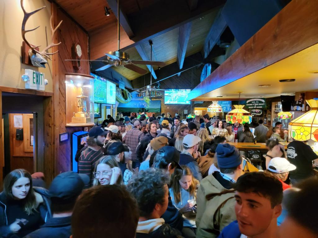 A crowded, dimly lit bar with many people socializing indoors.