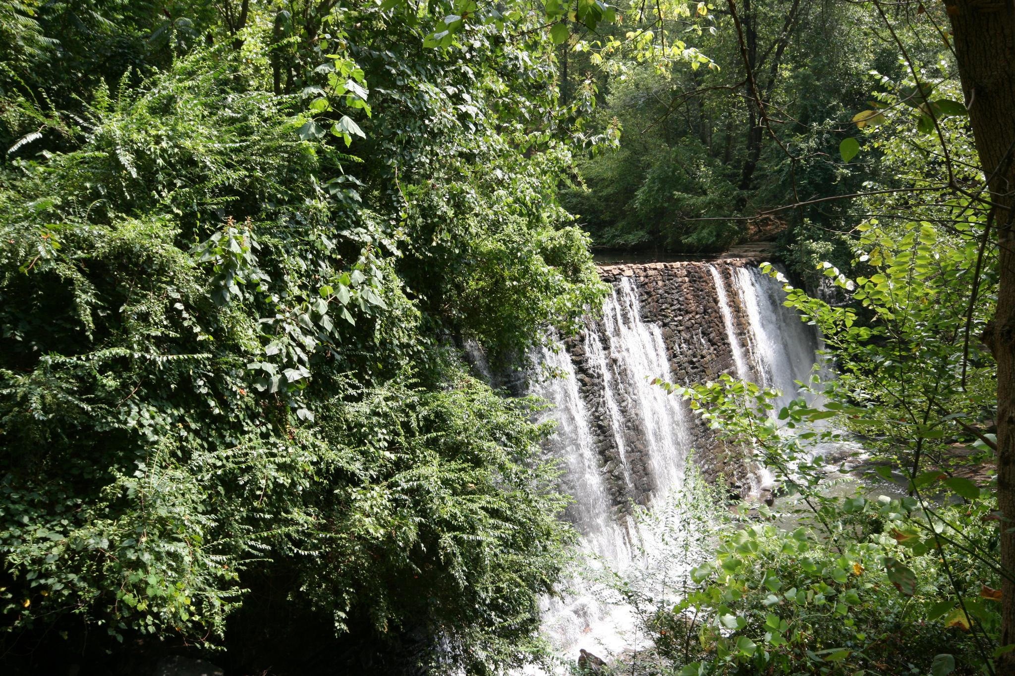 A beautiful waterfall cascades over a rocky wall, surrounded by lush green trees.