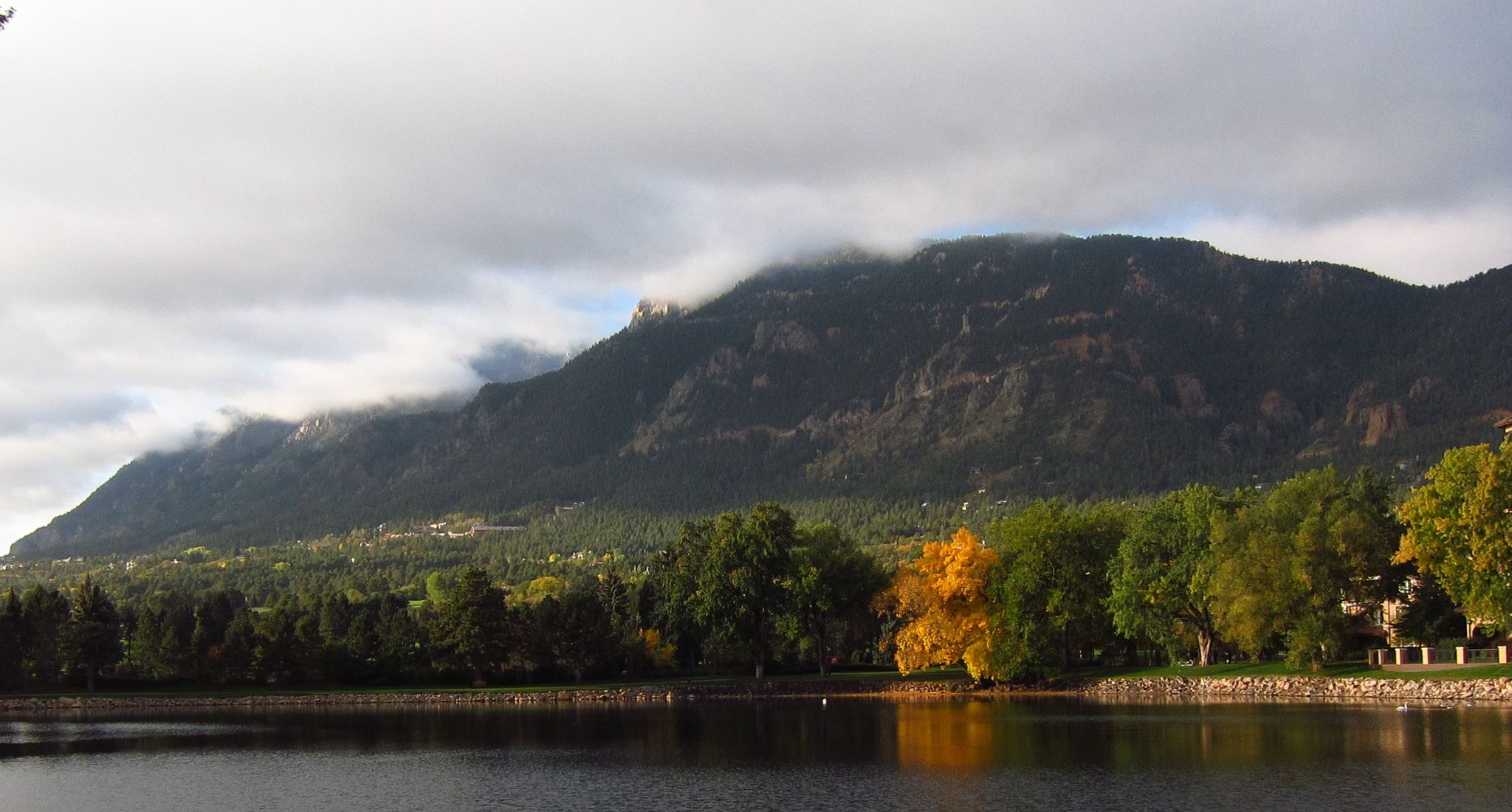 Lake reflecting mountains and autumn trees under cloudy skies. - The Broadmoor loop