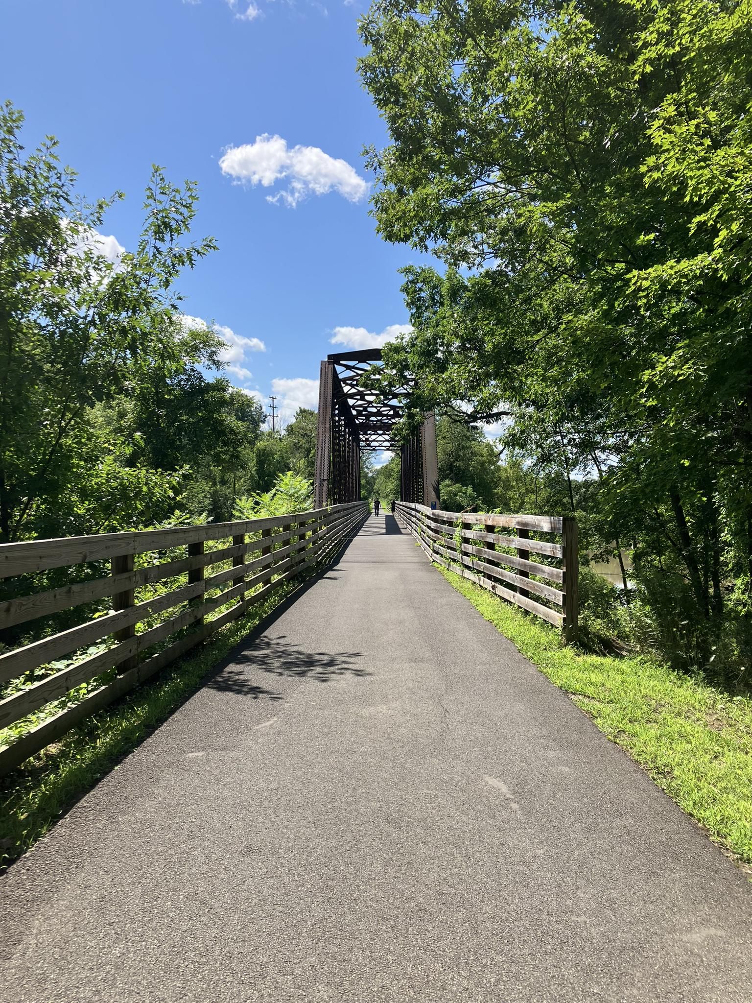 Paved path leading to a metal truss bridge under a bright blue sky. - Slingerlands Rest Stop loop from Schuyler Mansion State Historic Site