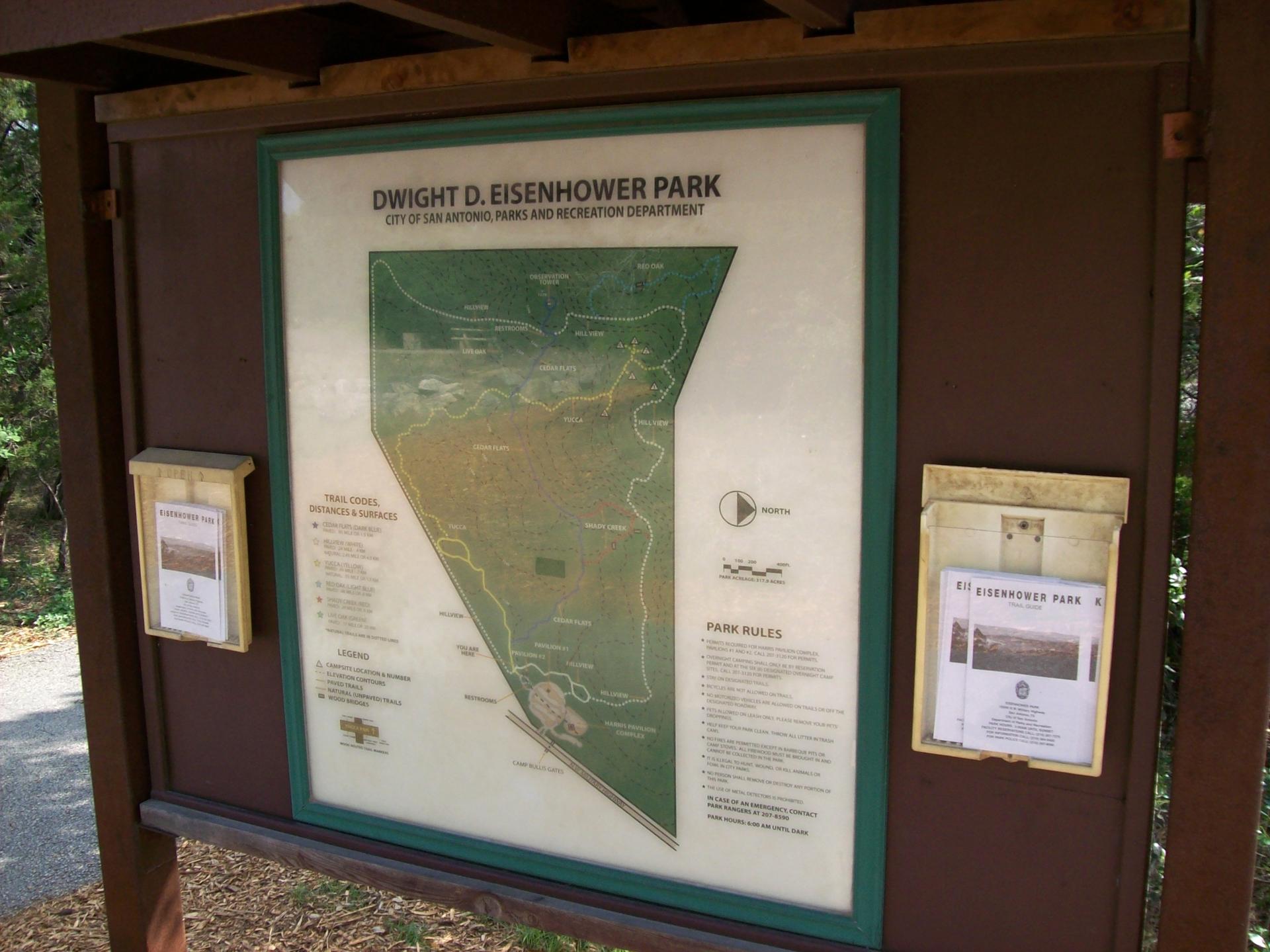 A brown display board shows a park map and information under bright light.