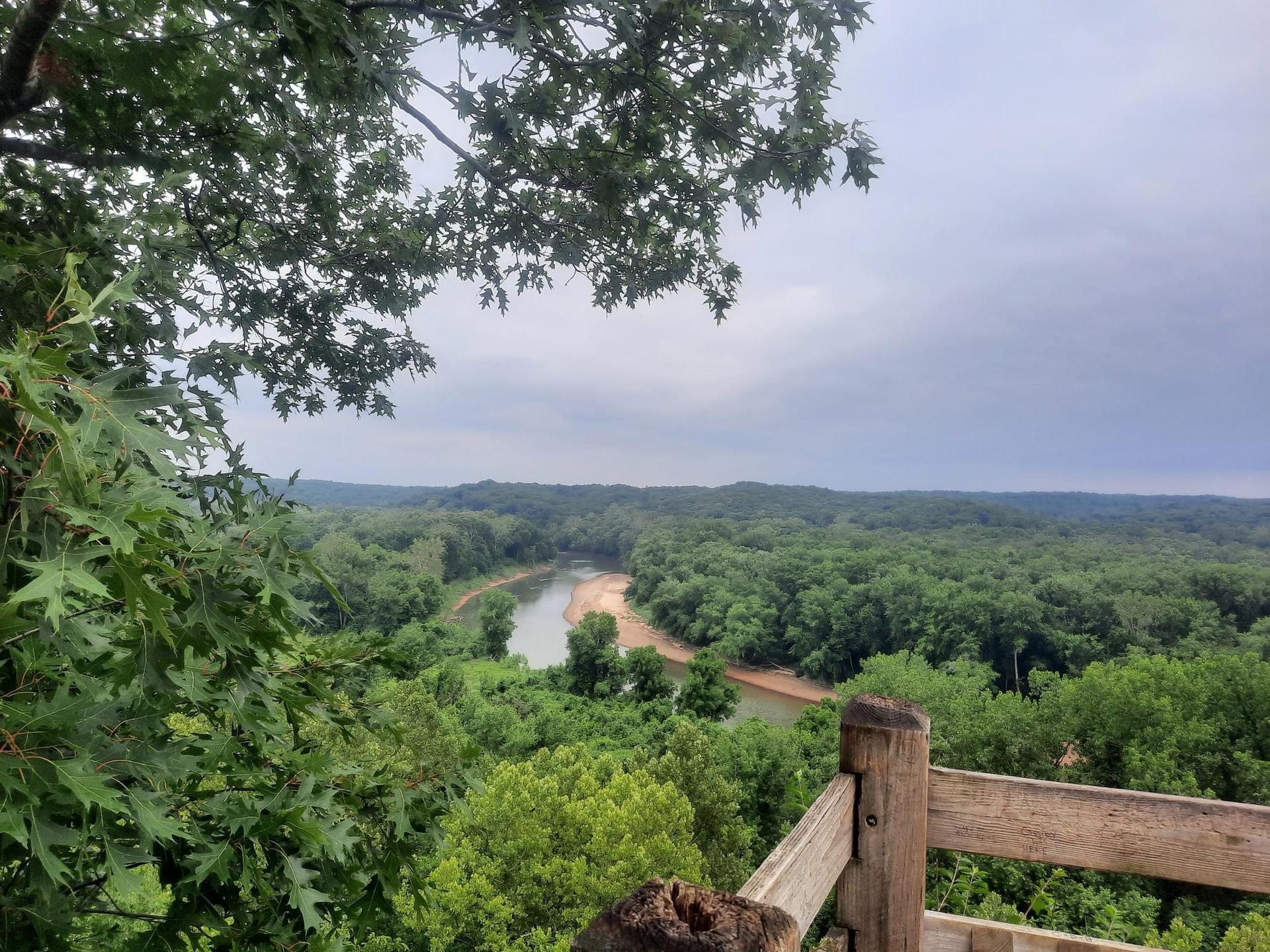 Overcast view of a winding river through a dense green forest.
