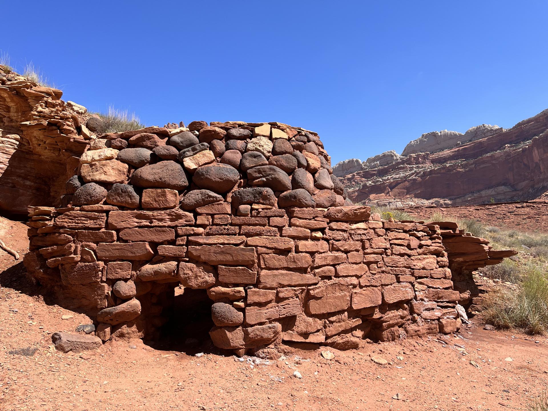 Ancient stone structure made of red rocks in a desert landscape.