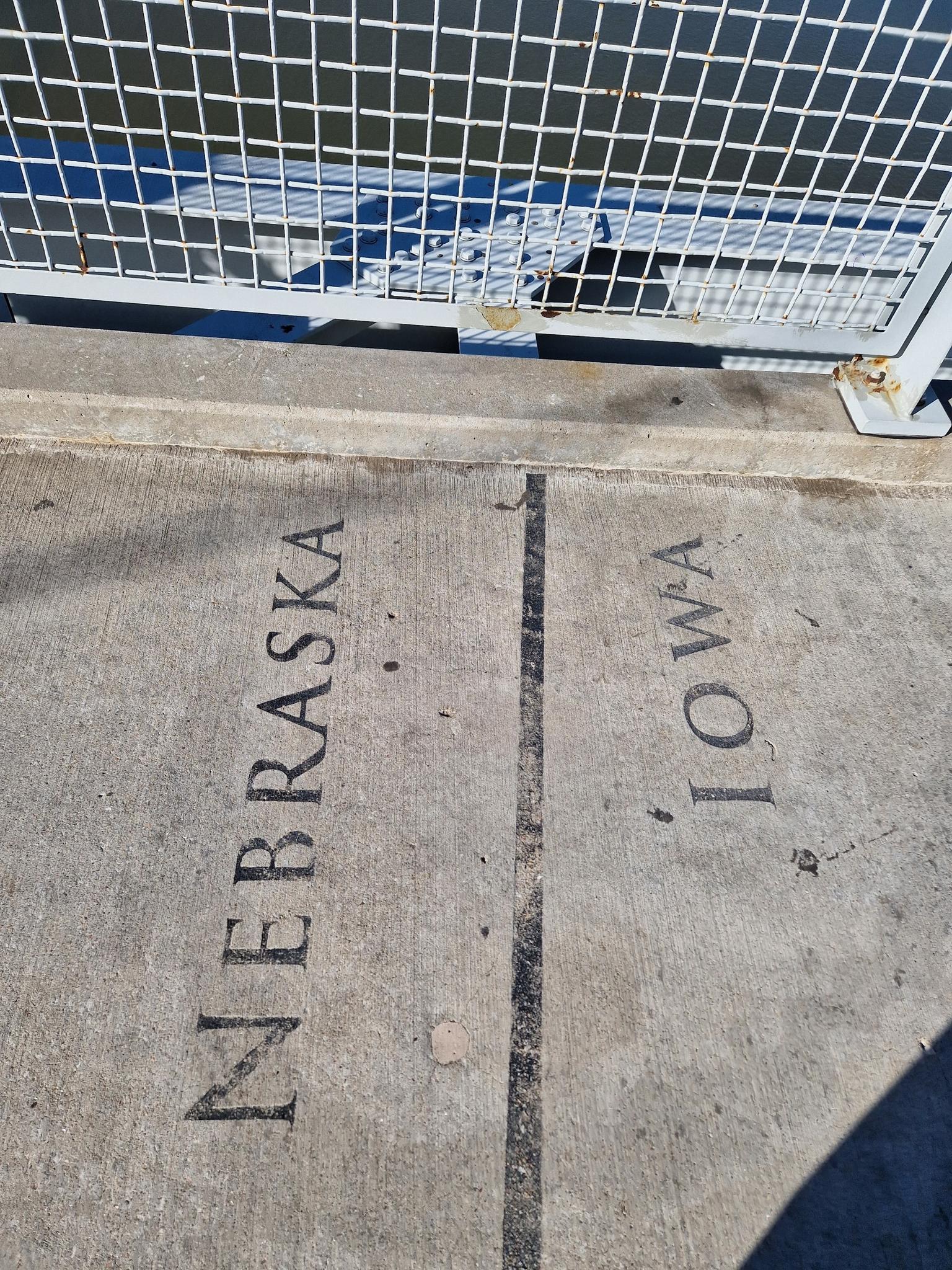 Concrete ground with 'NEBRASKA' and 'IOWA' painted, separated by a line.