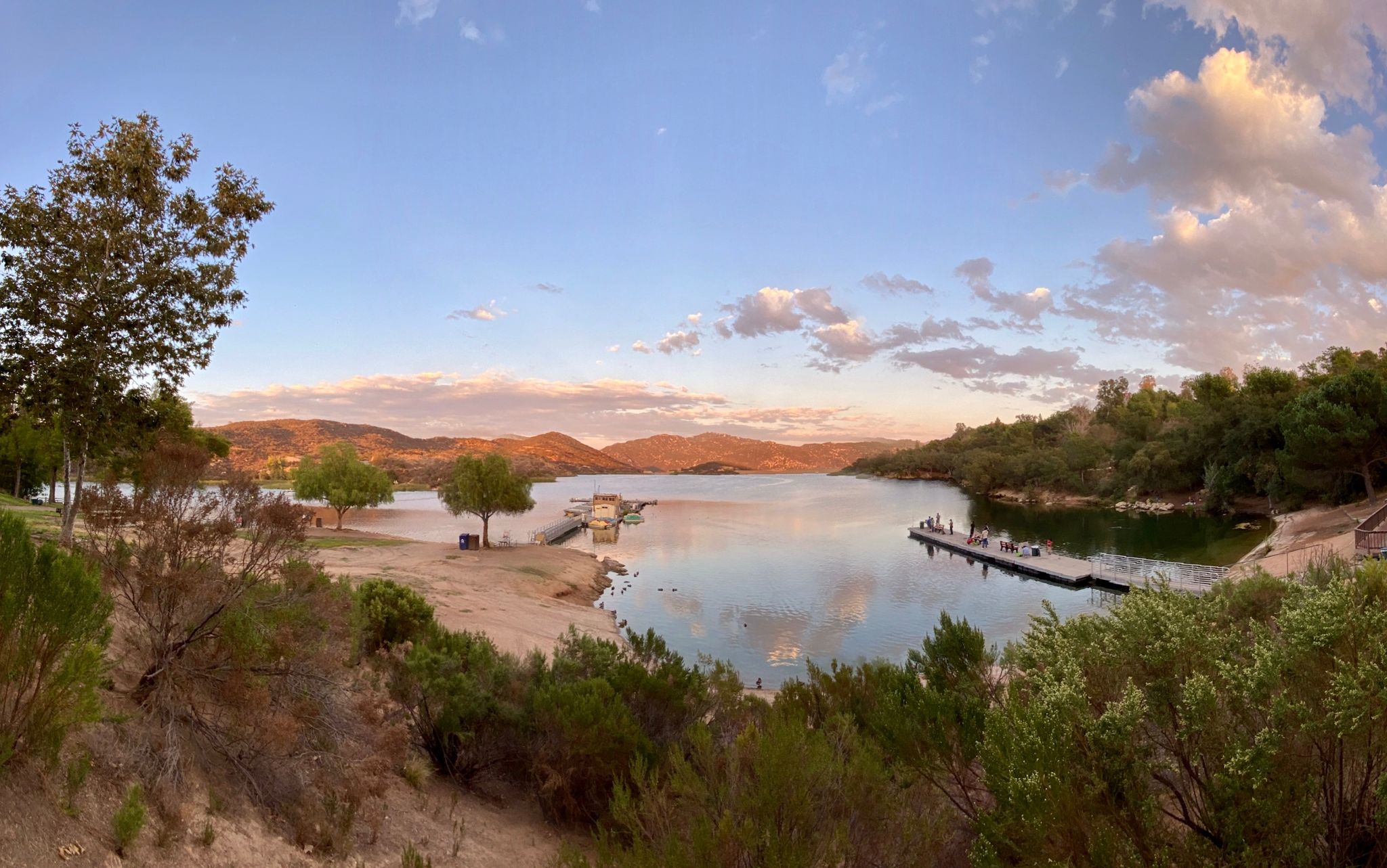 Panoramic lake view at sunset with distant hills and people on a floating dock. - Dixon Lake North Shore Trail