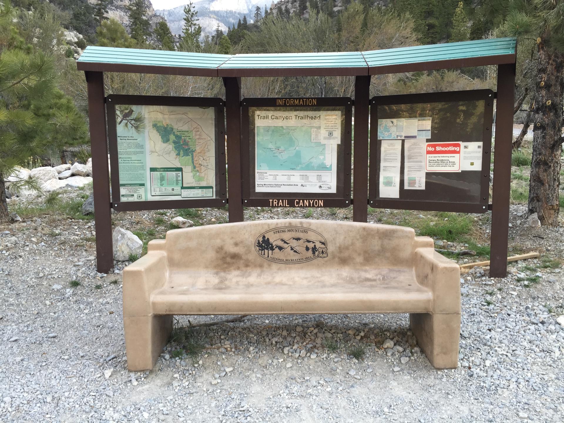 An information board and a stone bench on a gravel path.