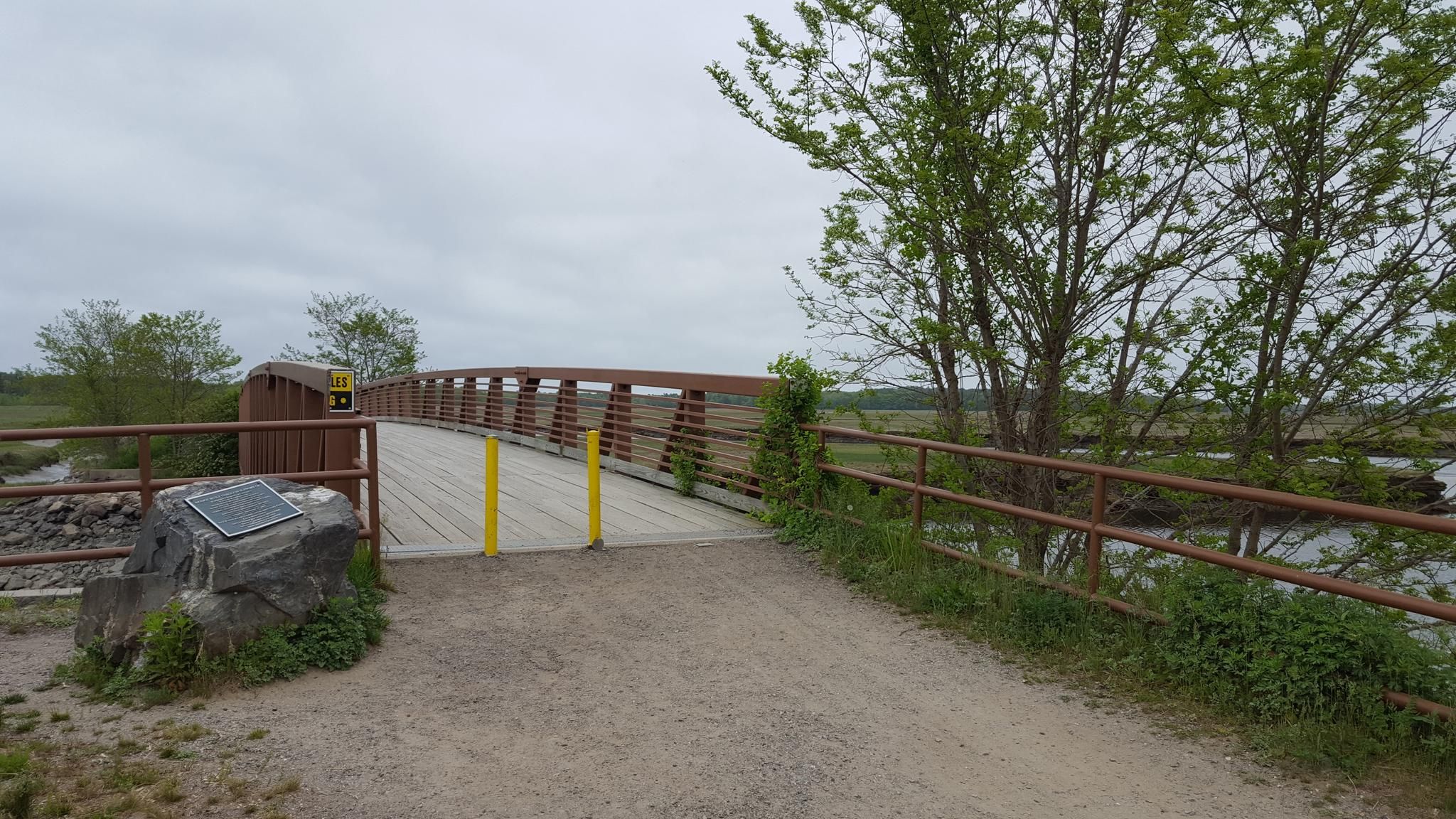 A wooden bridge over water under an overcast sky. - Eastern Trail