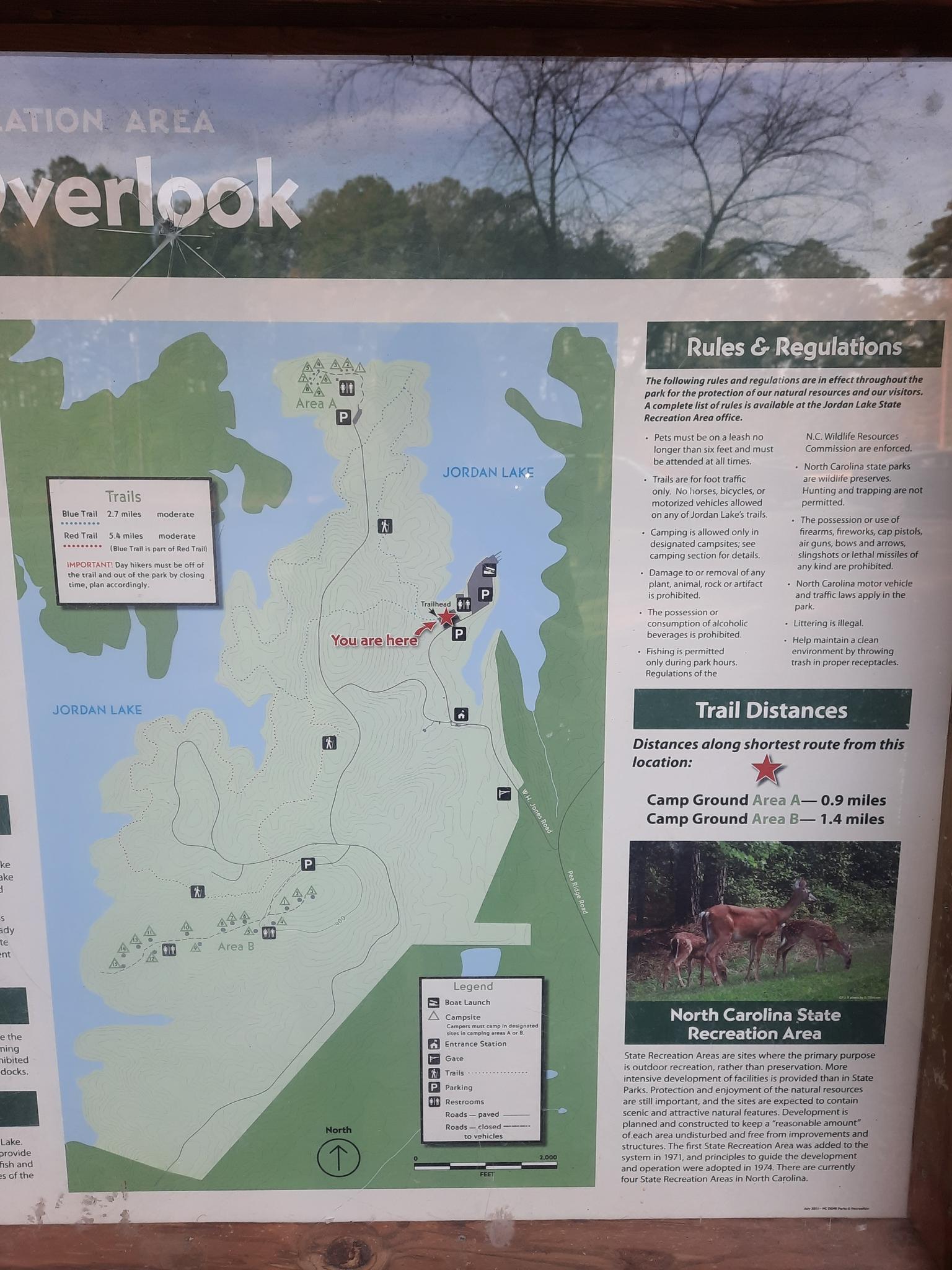 A close-up of an outdoor information board with a trail map and rules.