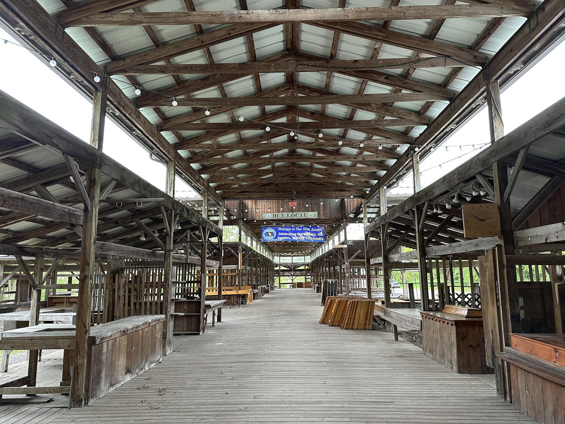 An empty, long wooden market hall with numerous stalls and a high ceiling.