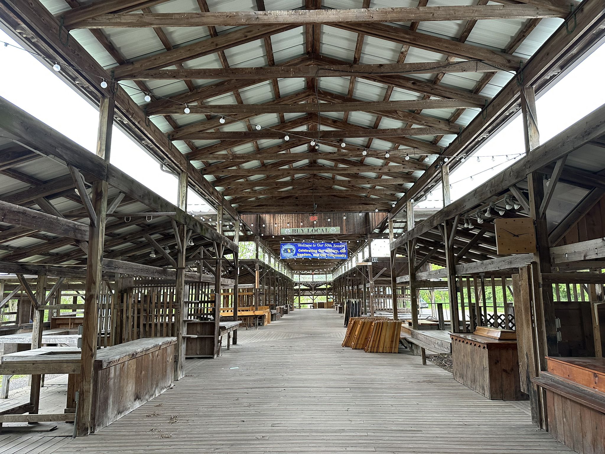 An empty, long wooden market hall with numerous stalls and a high ceiling. - Cayuga Waterfront Trail