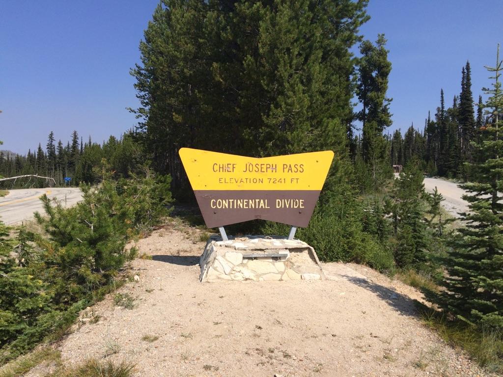 A yellow and brown sign on a stone base stands under a clear sky.