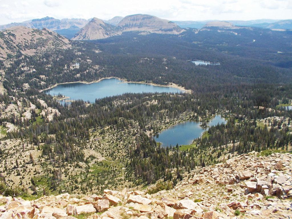 Aerial view of multiple blue lakes surrounded by green forests and mountains.