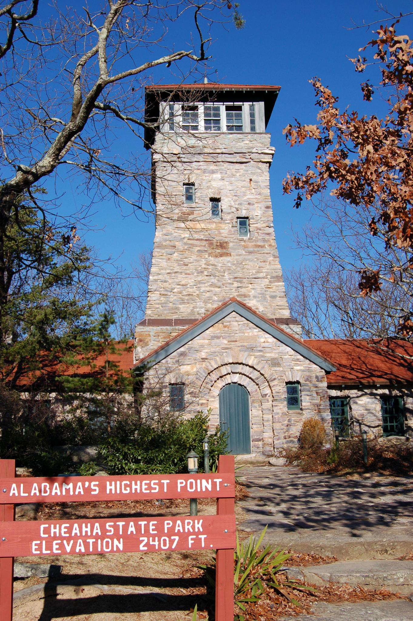 Tall stone tower building with a red roof under a clear blue sky.