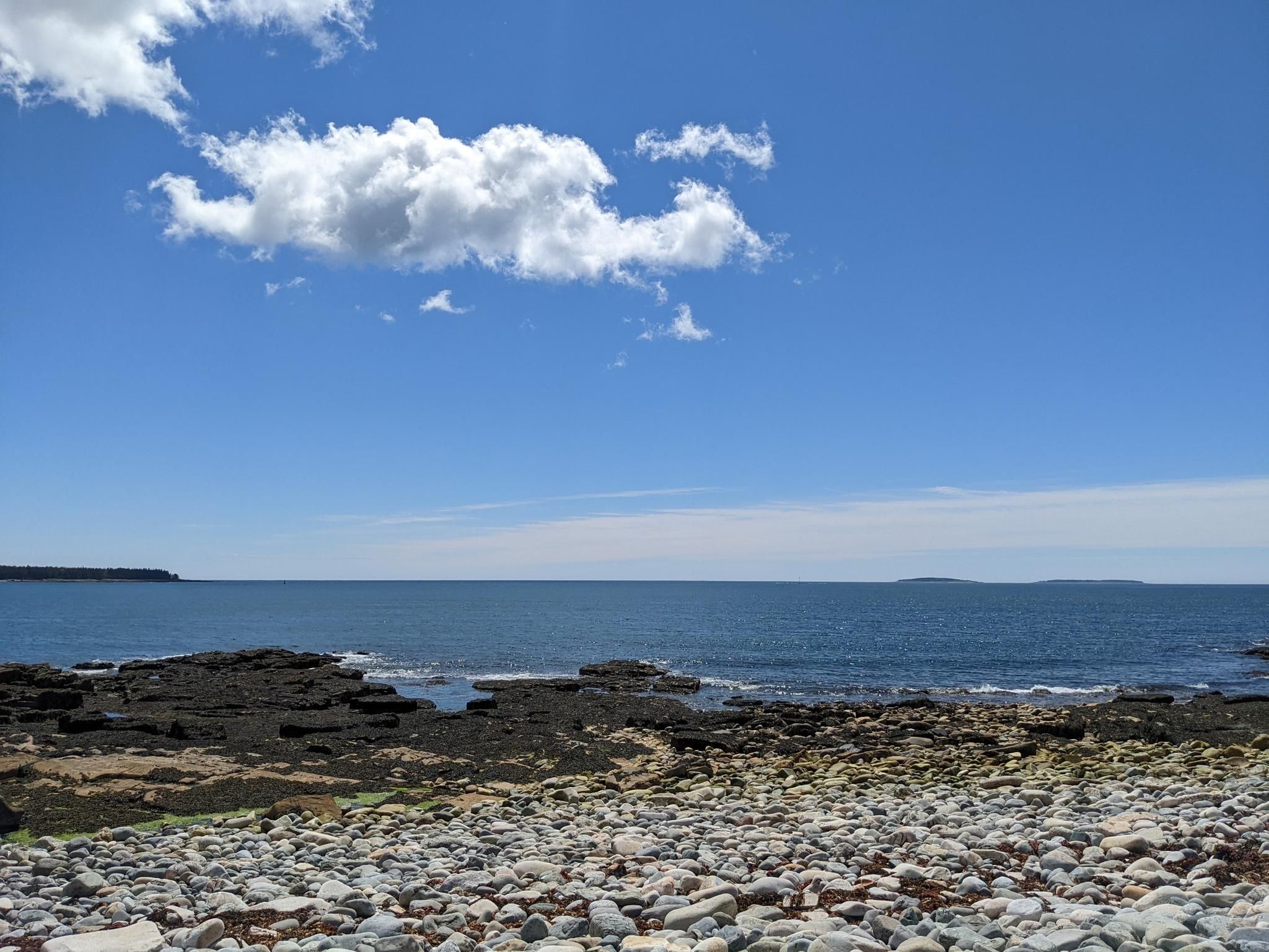 Sunny day over a rocky beach and calm blue ocean with white clouds. - Southwestern Mount Desert Island loop