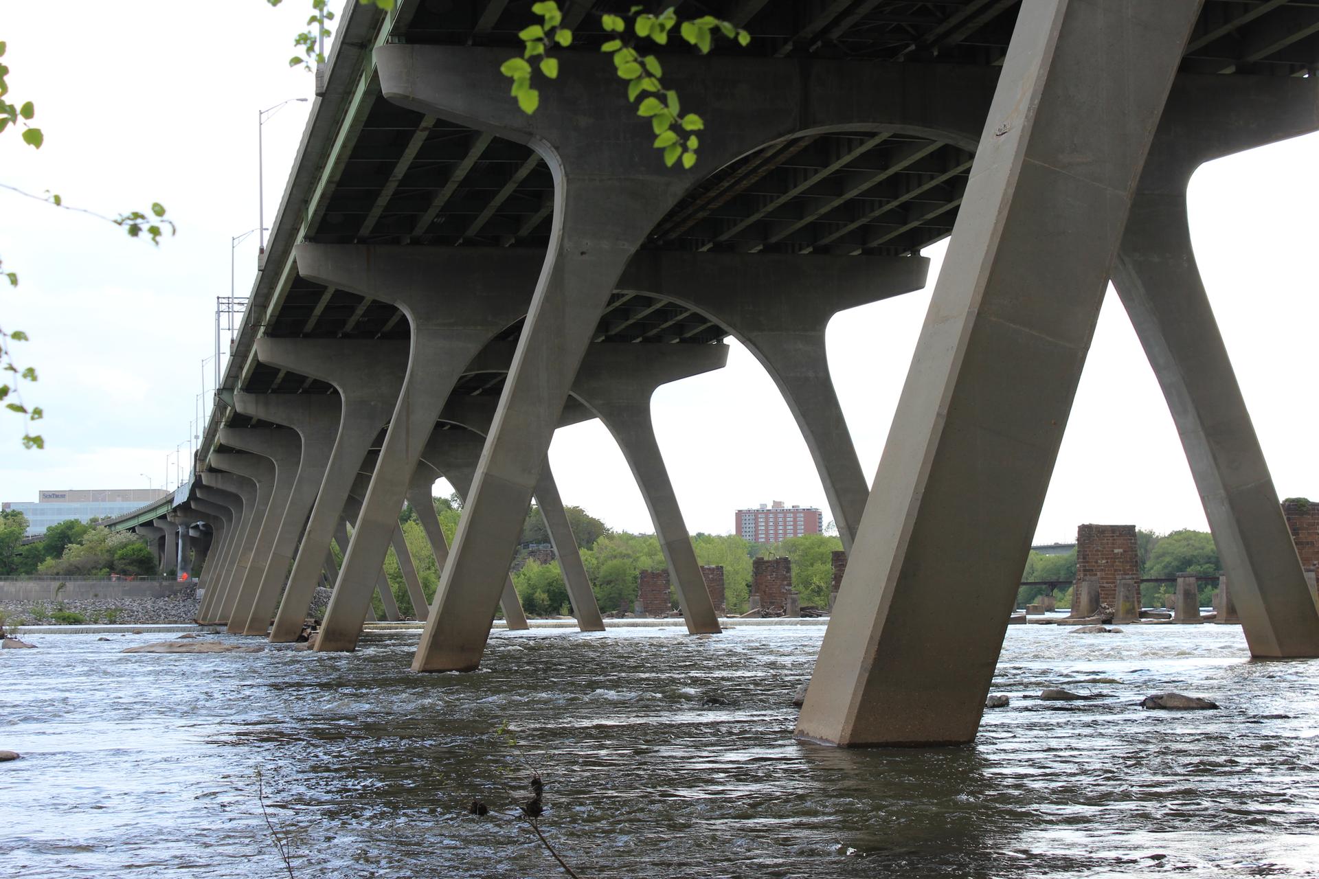 View from under a large concrete bridge over flowing water.