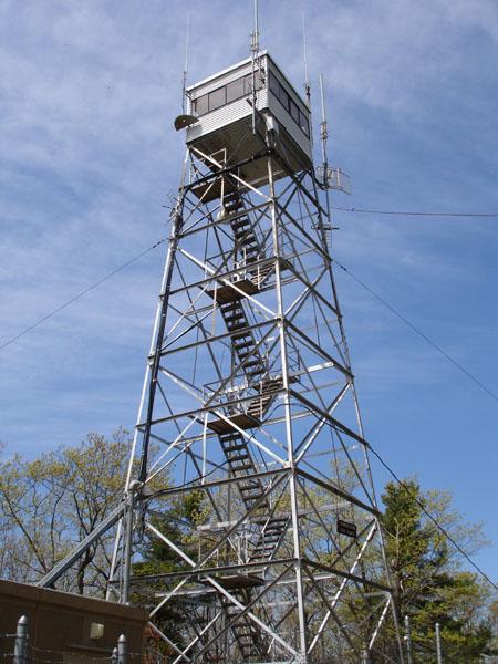 Tall metal fire lookout tower against a bright blue sky.