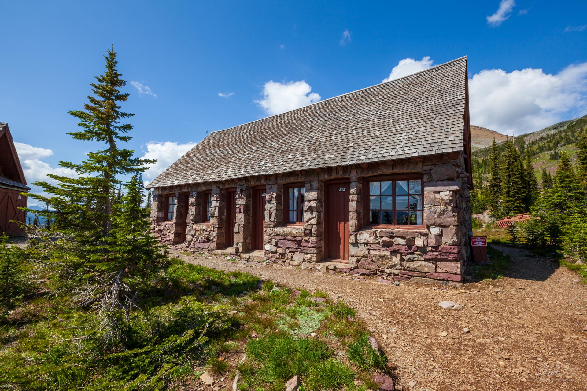 A rustic stone and wood cabin under a bright blue sky.