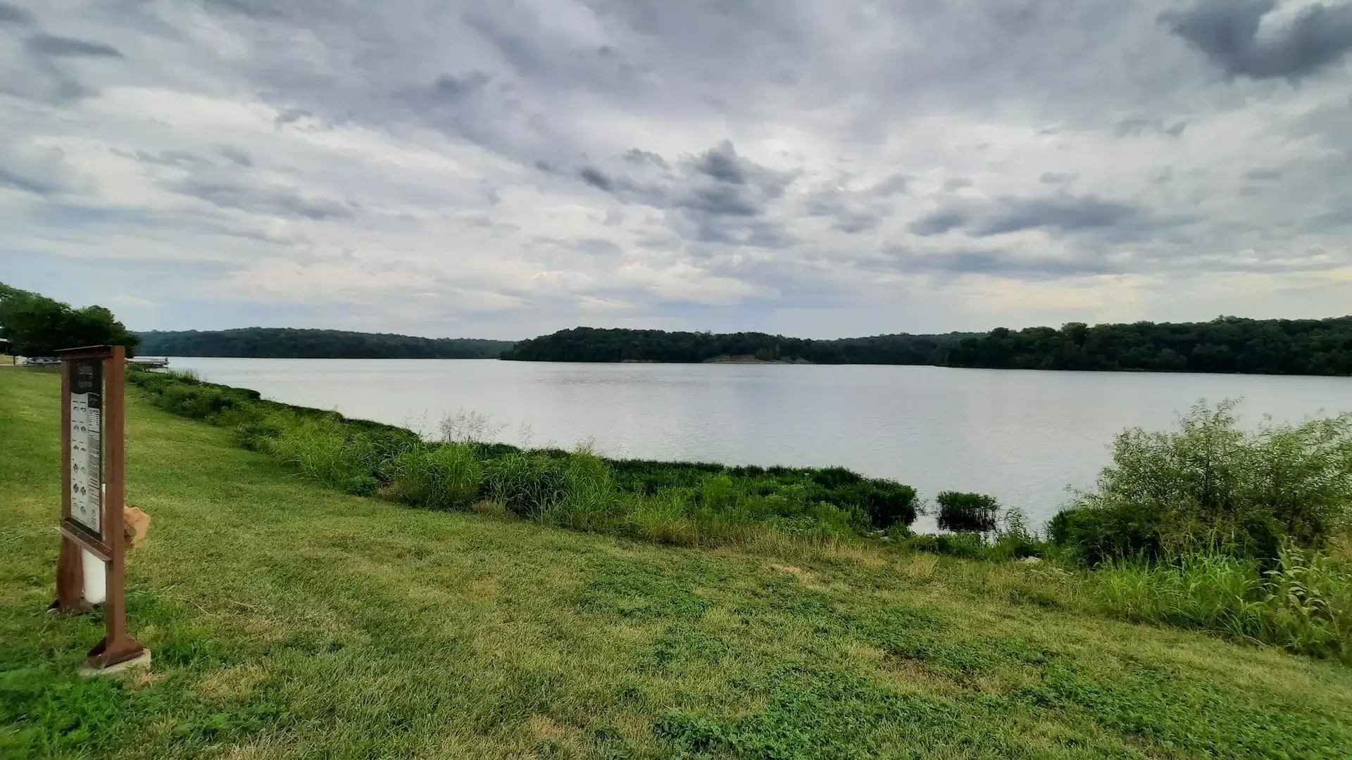 Wide lake view with green banks under a cloudy sky.