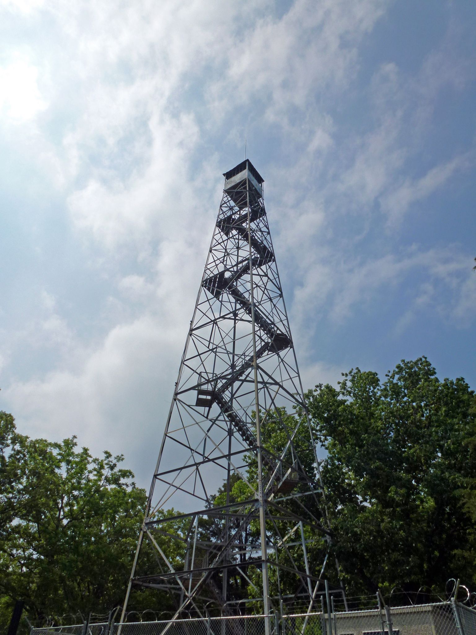 Tall metal observation tower with spiral stairs against a blue sky and green trees. - Hercules Glade Backpacking Loop