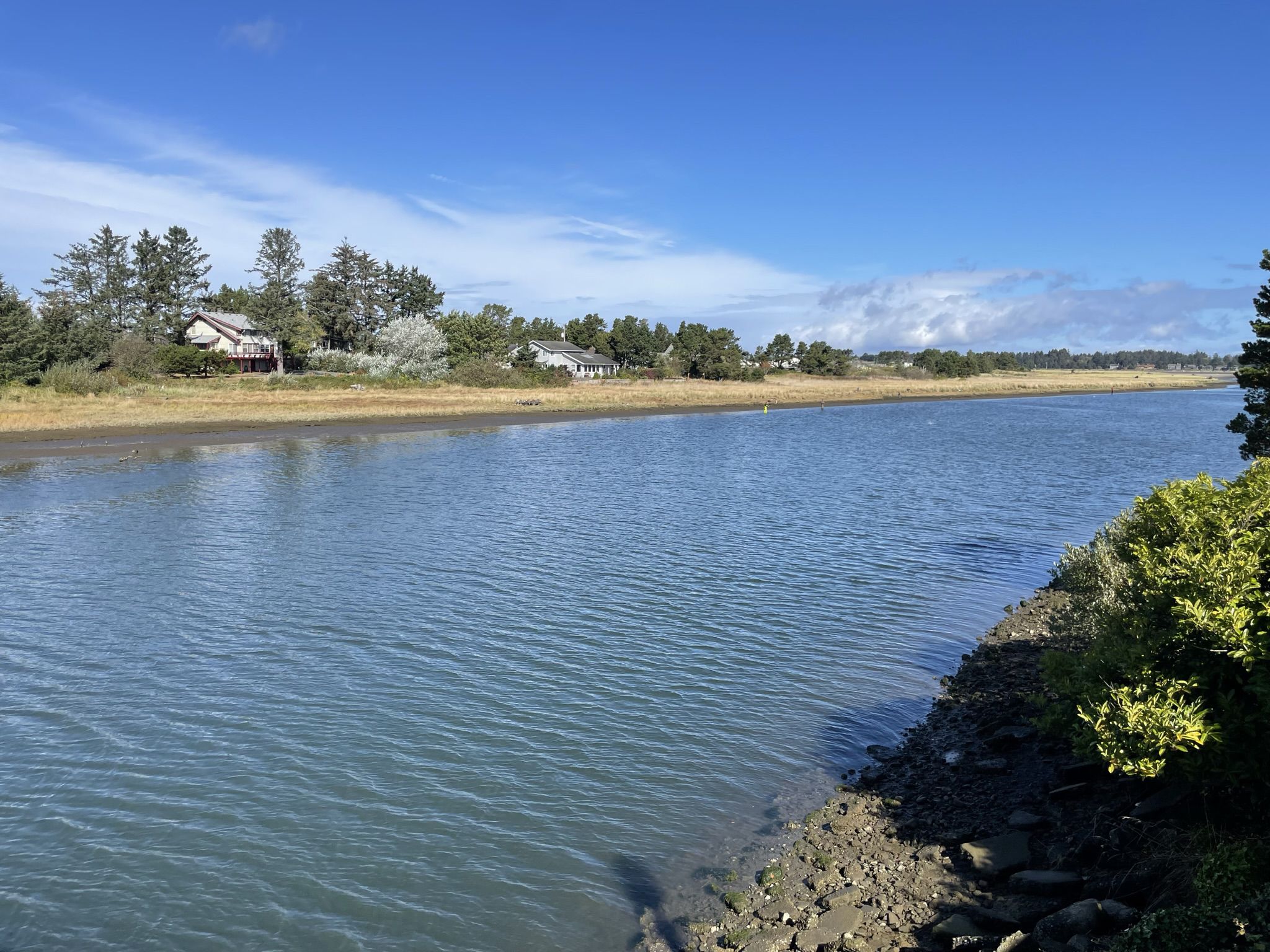 A wide river with houses and trees on the distant bank, under a sunny sky. - TransAmerica Trail
