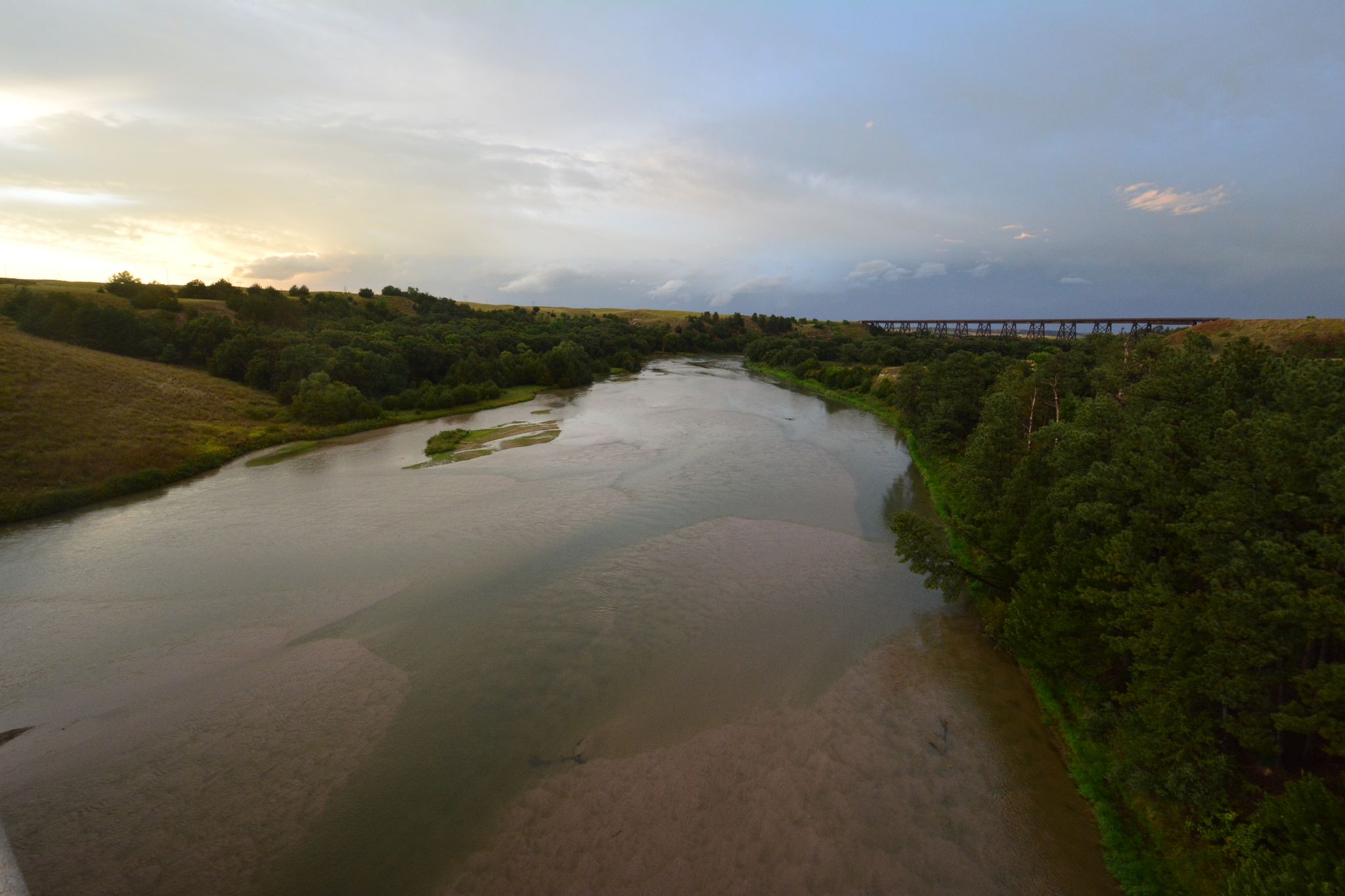 Wide river winding through a green valley under an overcast sky. - Jim MacAllister Nature Trail