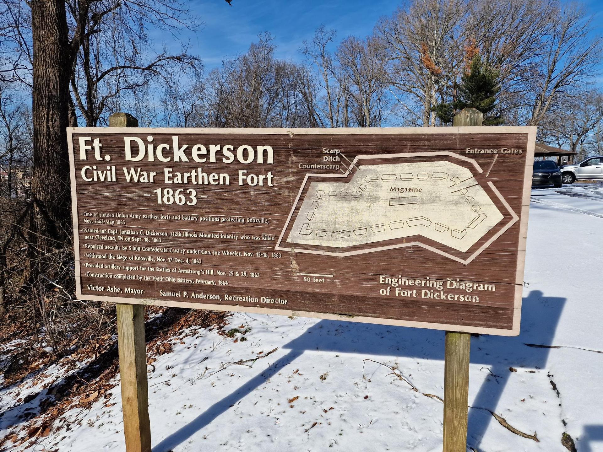 A brown historical sign with a fort diagram on snowy ground.