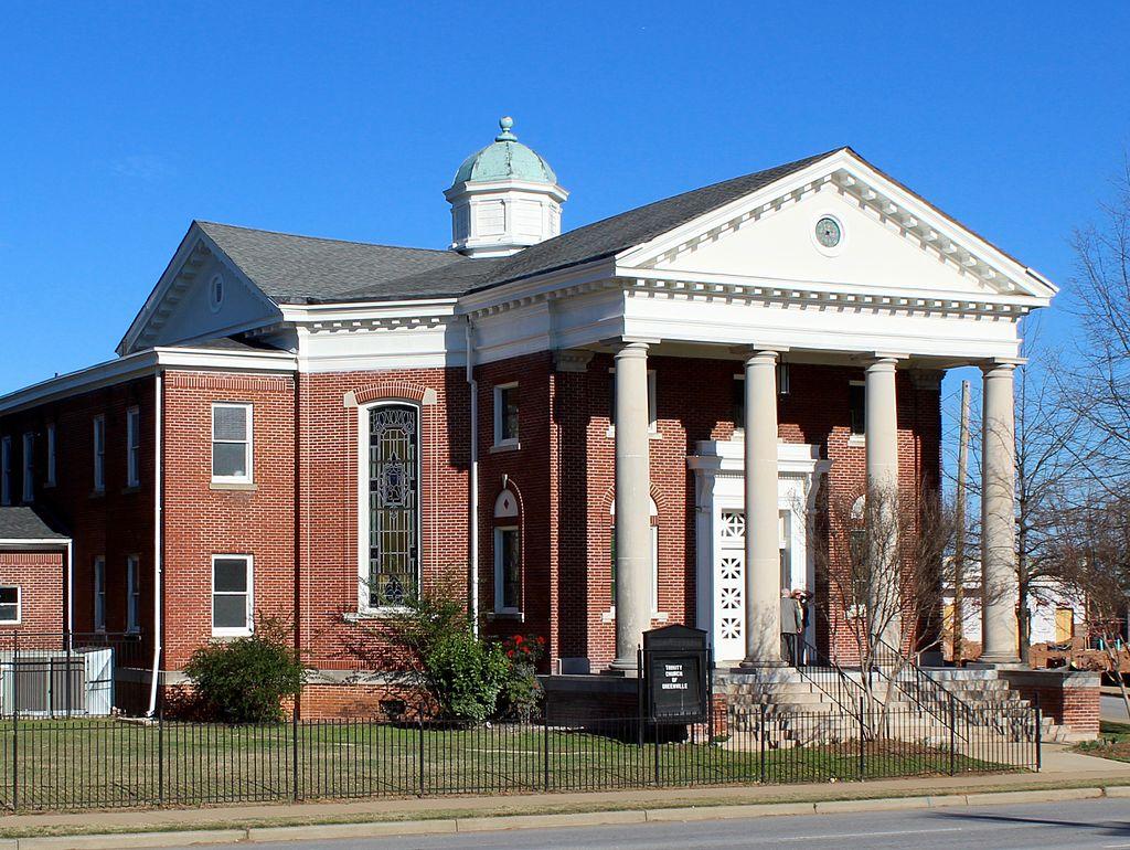 Large brick building with white columns and a dome under a clear blue sky.