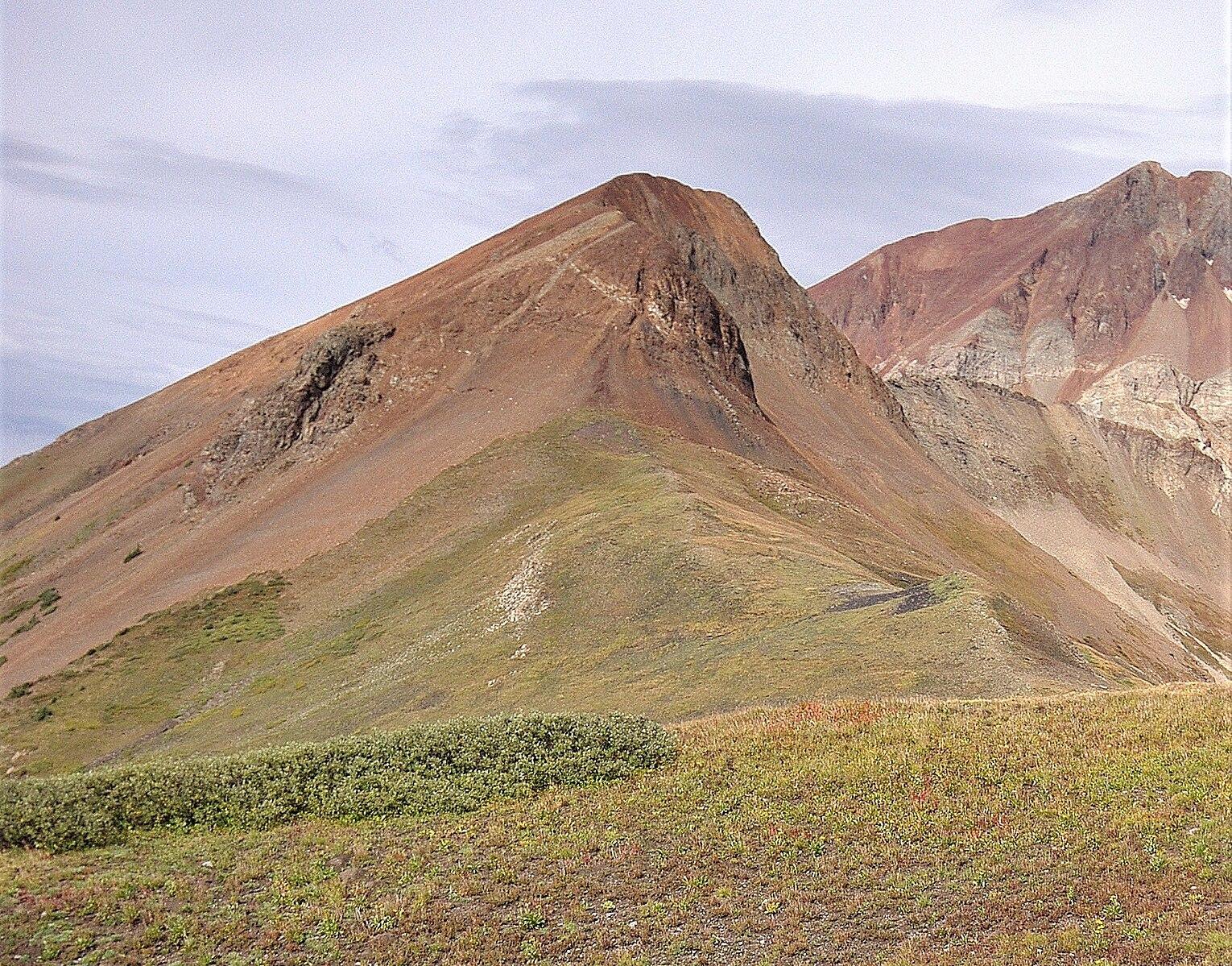 Gently sloping mountains with green and brown terrain under a cloudy sky.