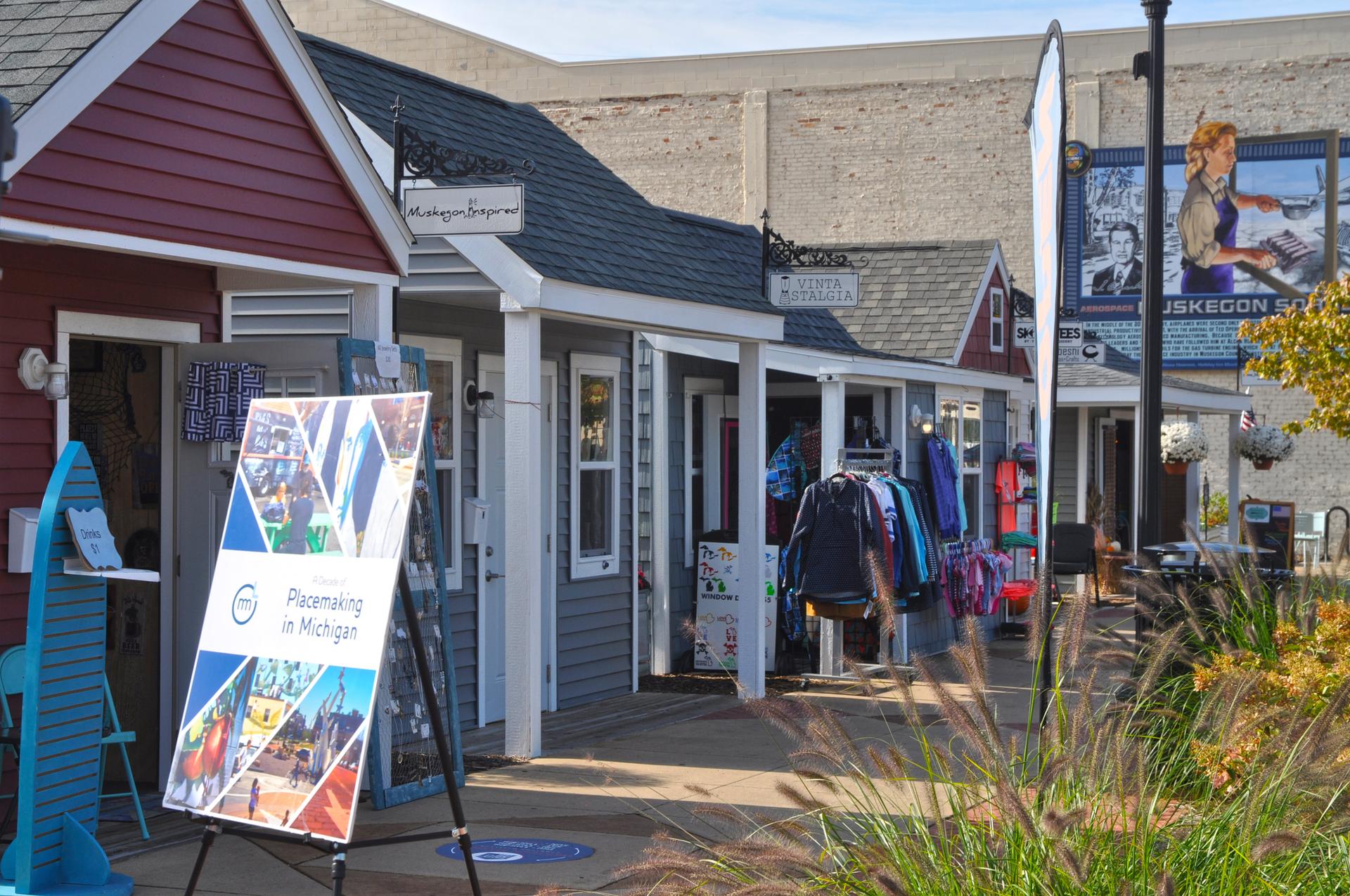 Small, colorful shops display merchandise outdoors on a bright day.