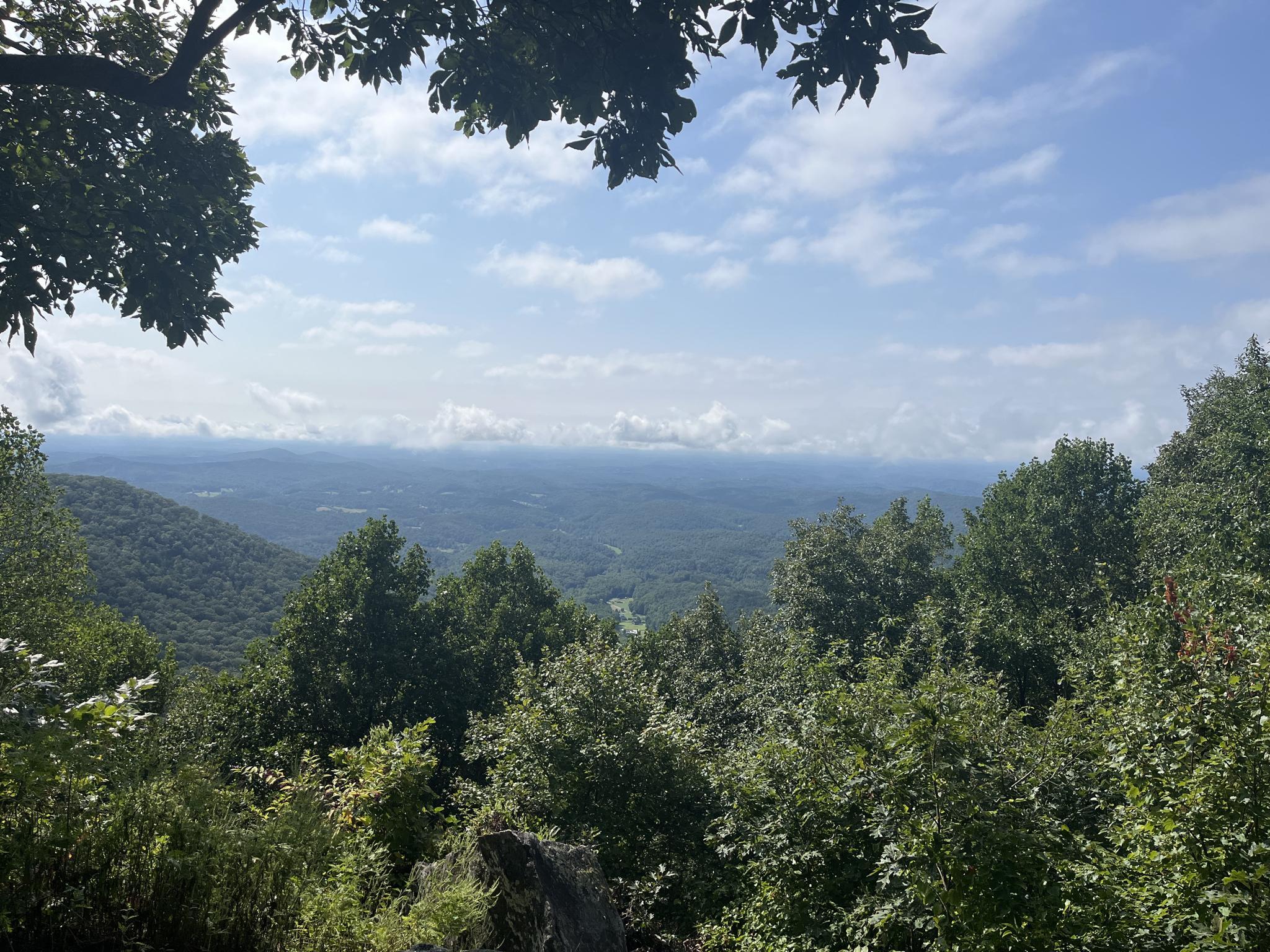 Expansive mountain view with green trees under a blue sky.
