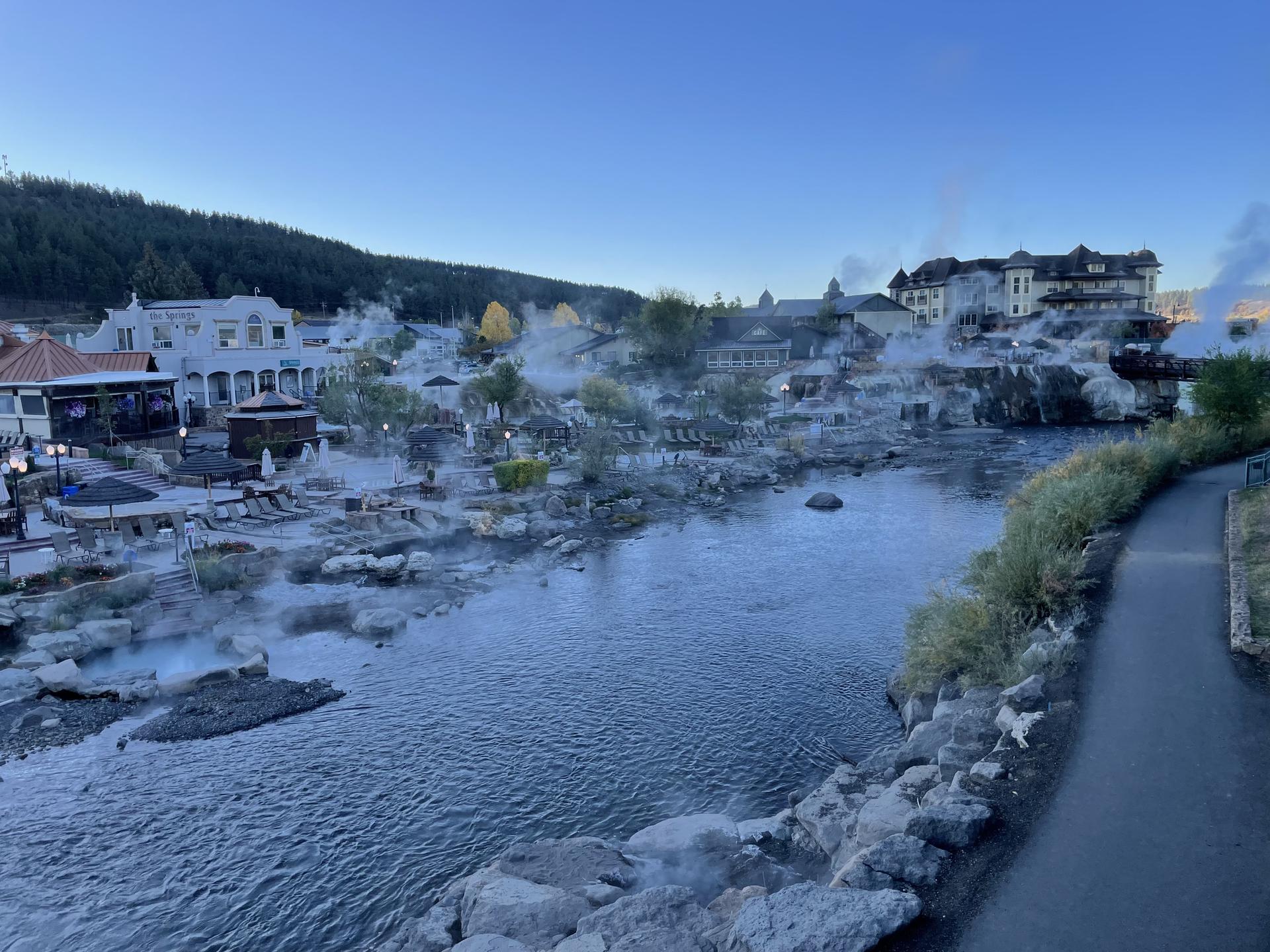 Early morning view of a river with steam rising near buildings.