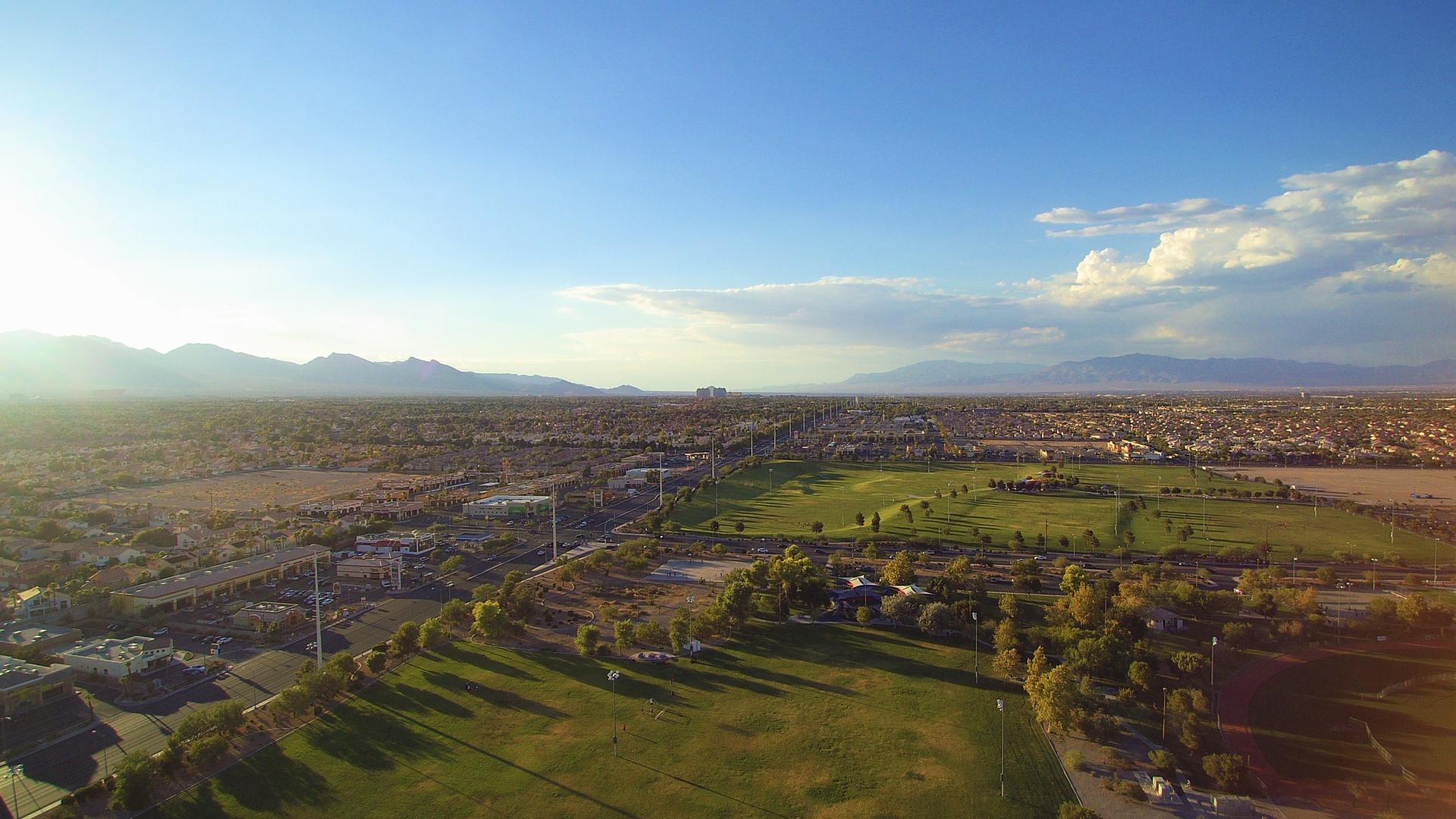 Expansive aerial view of green golf courses, desert, and distant mountains.