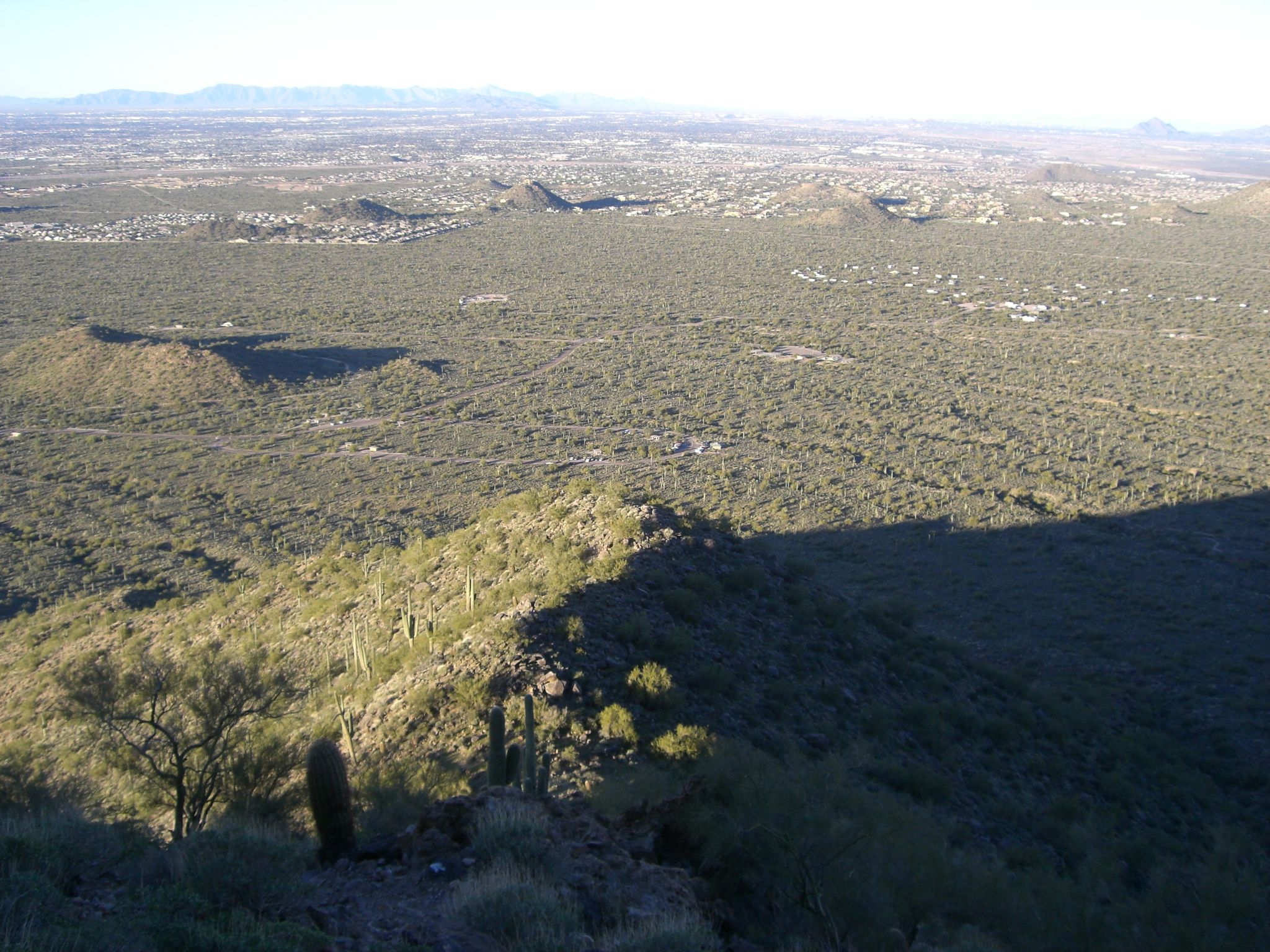 Expansive desert landscape from above, with distant city and long shadows. - Usery Mountain via L'Alpe d'Huez Trail