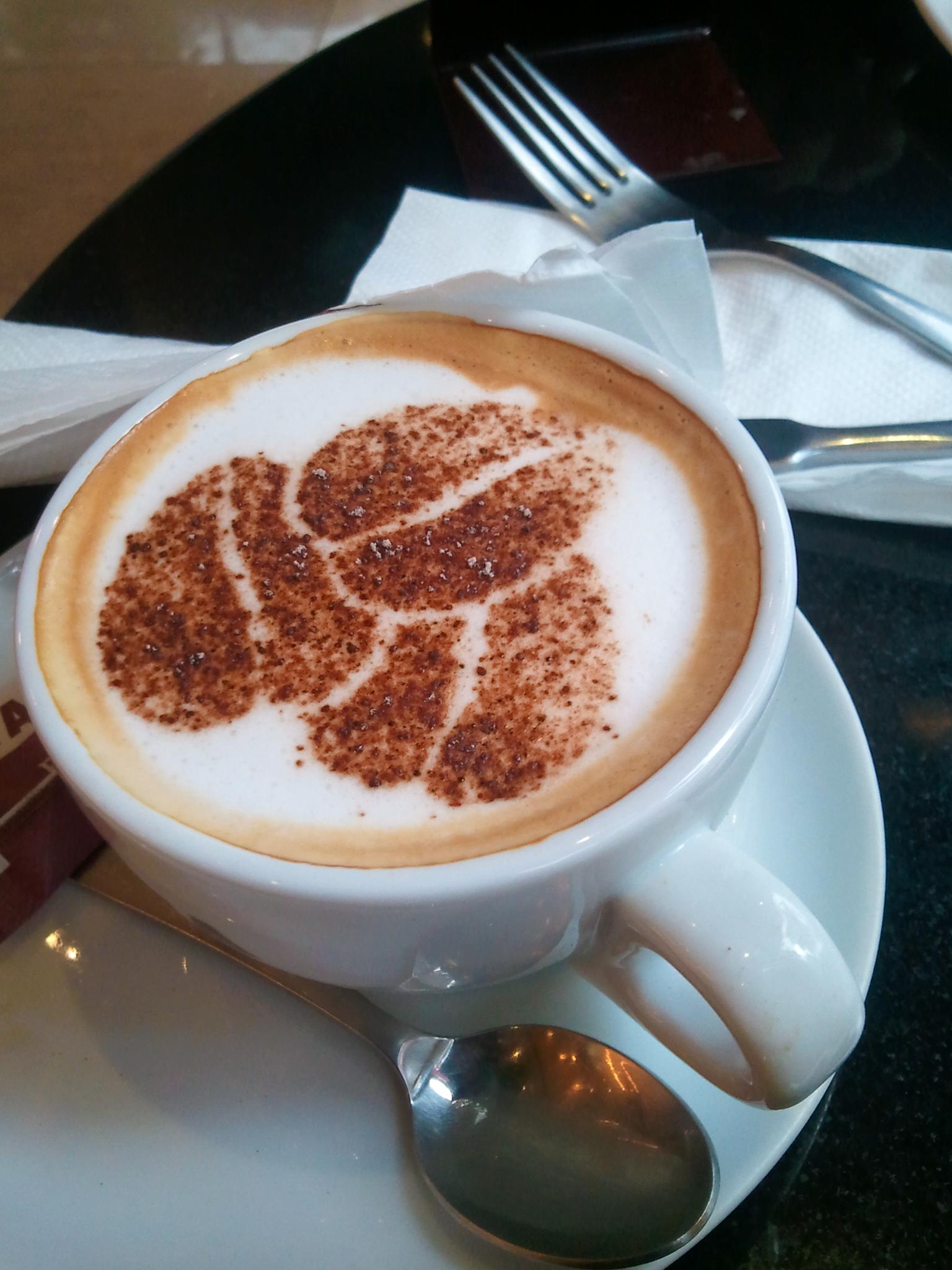 A close-up of a cappuccino with intricate foam art on a table.