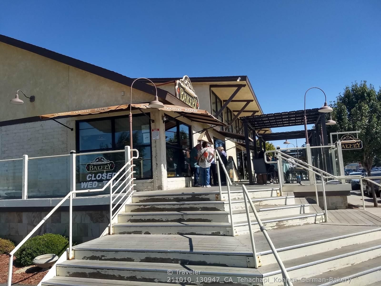 People stand on steps outside a modern building under a clear blue sky.