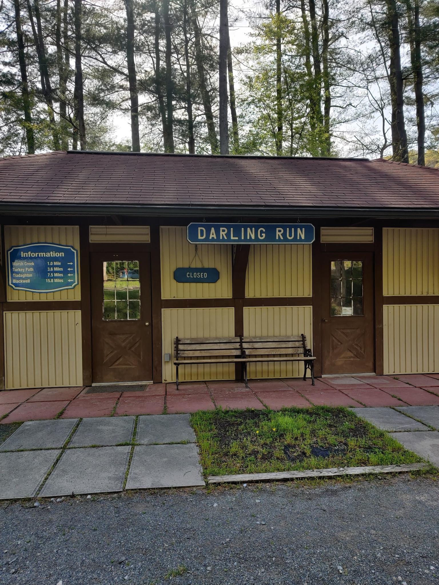Small yellow building with a 'DARLING RUN' sign and benches outside.