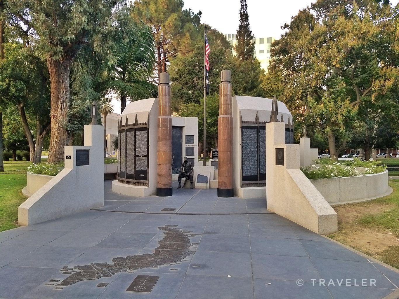 Circular stone monument with plaques and columns in a green park.