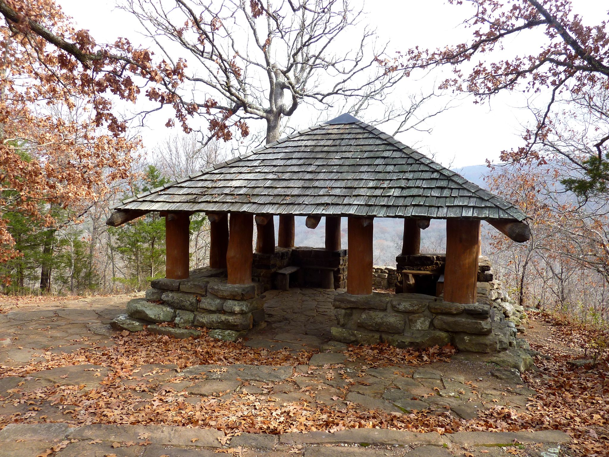 Rustic wooden gazebo with shingled roof, surrounded by autumn leaves and bare trees. - Yellow Rock Trail