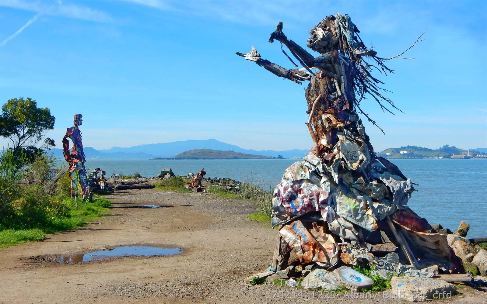 Large metal sculptures by the water's edge on a bright, sunny day.