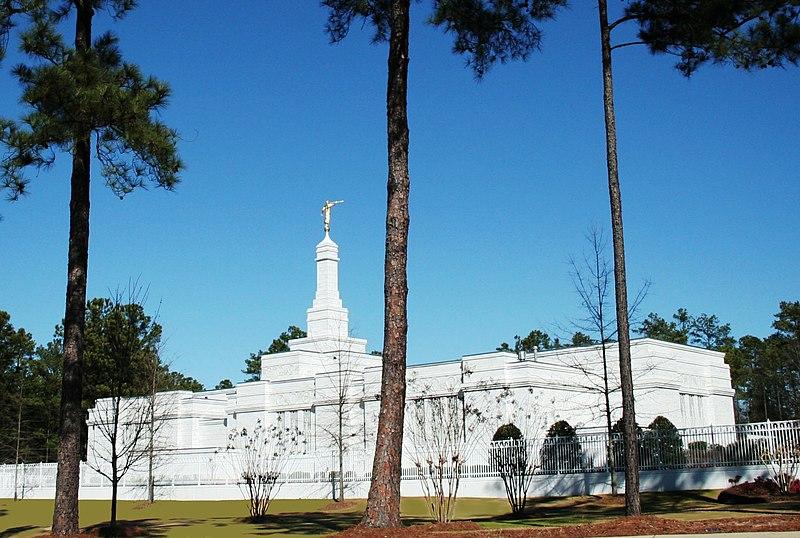 White building with a golden statue under a clear blue sky, framed by trees.