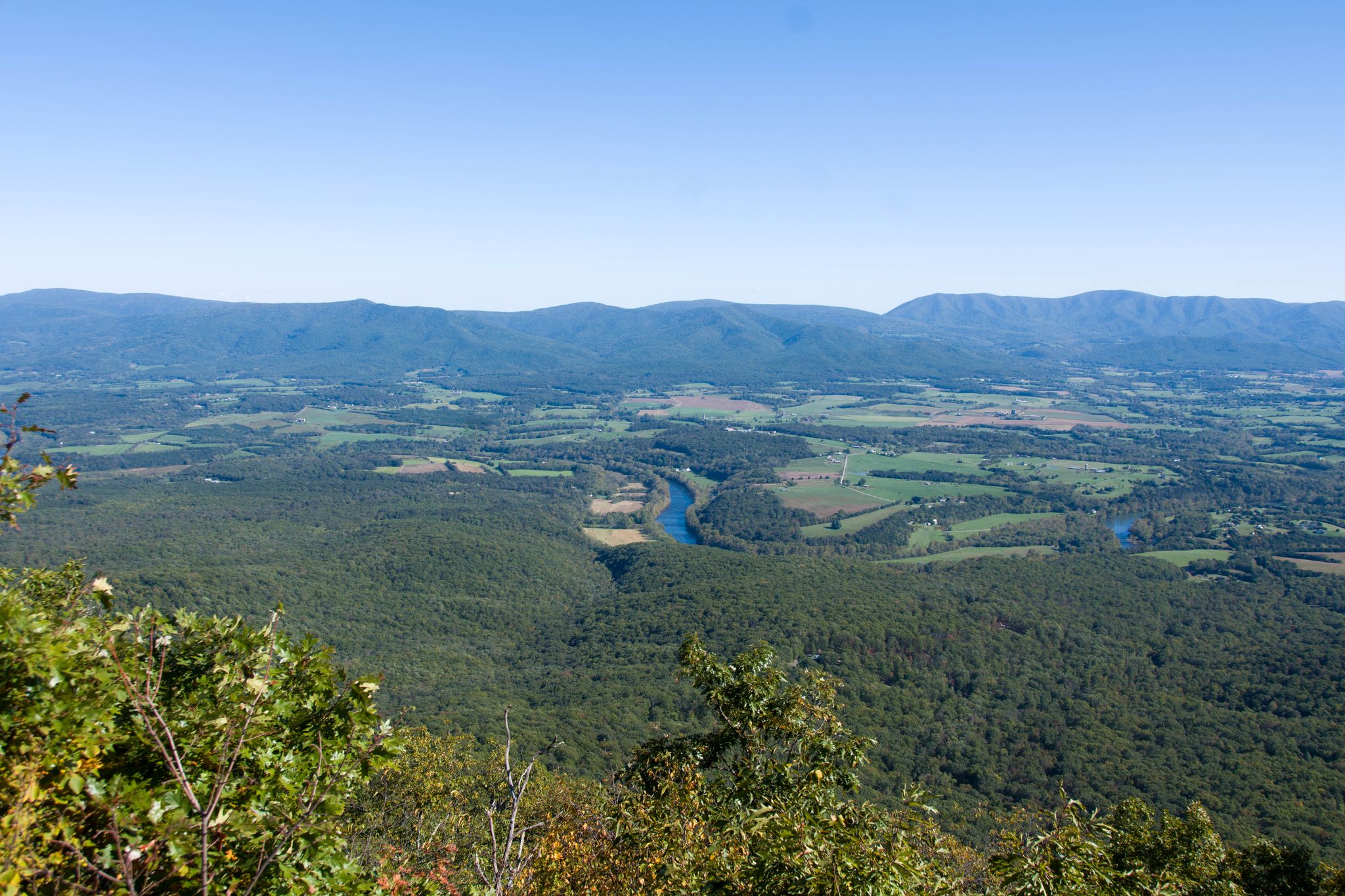 Panoramic view of a green valley with a winding river and distant mountains. - Kennedy Peak Loop