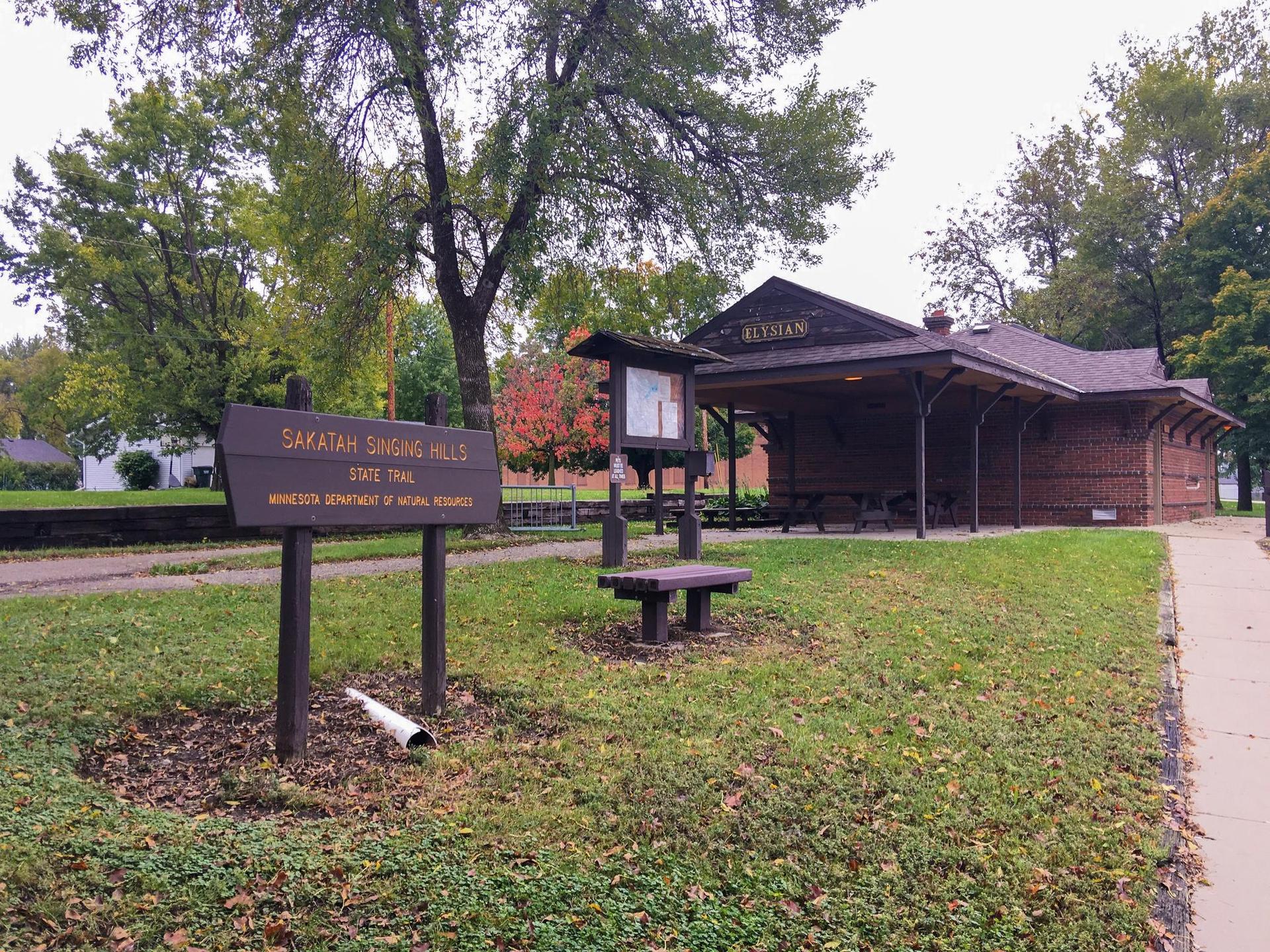 Wooden building and sign in a grassy park on an overcast day.