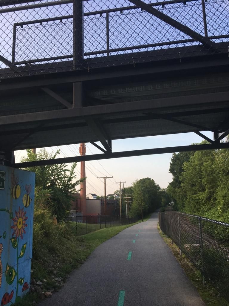 Paved path under a metal bridge, leading into a tree-lined area. - Ahern State Park Loop via WOW Trail
