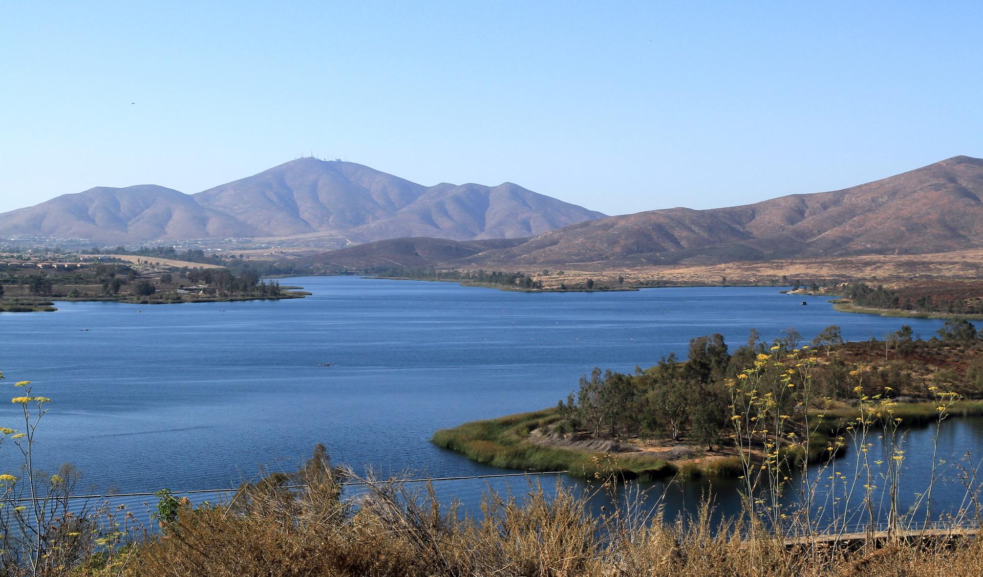 Wide view of a large blue lake surrounded by mountains on a clear day.