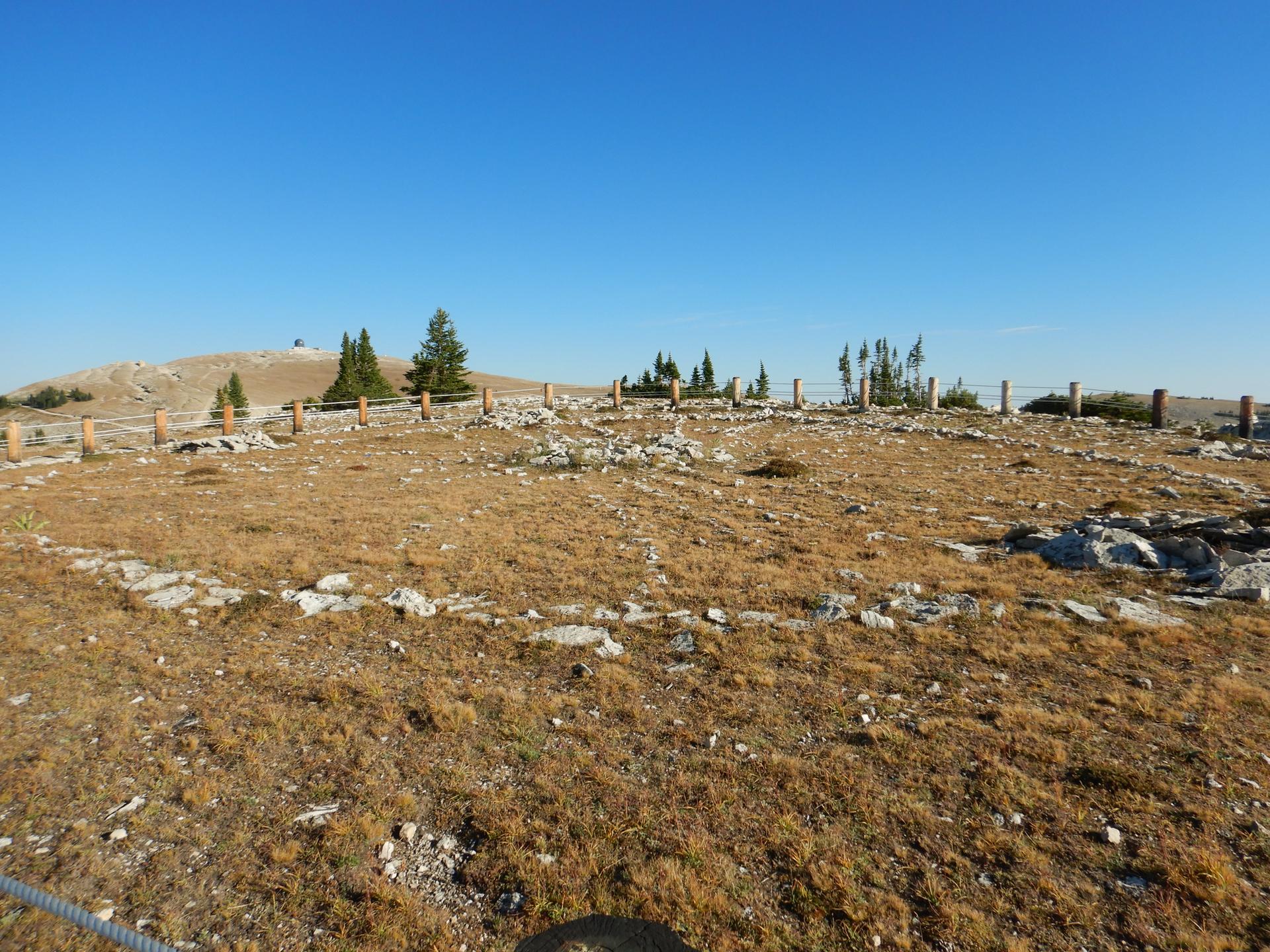 A dry, rocky landscape with a circular rock formation under a clear blue sky.