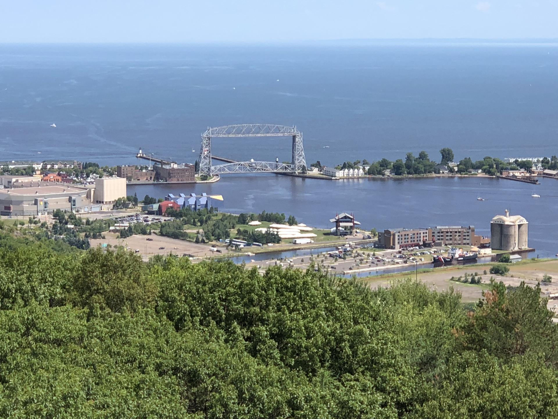Overhead view of a wide bay with a large bridge and coastal buildings.