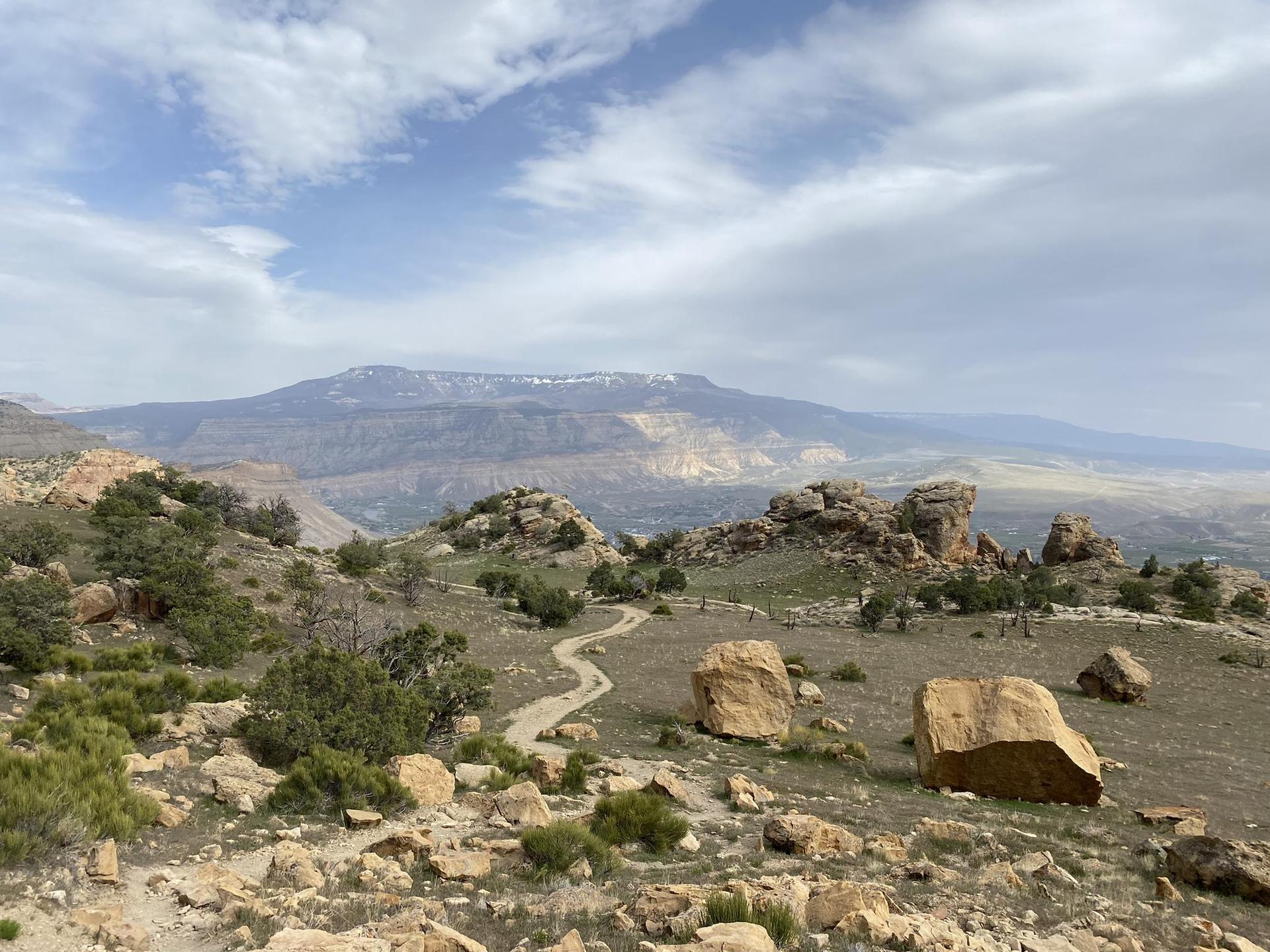 Winding dirt path through rocky terrain, leading to distant snow-capped mountains.