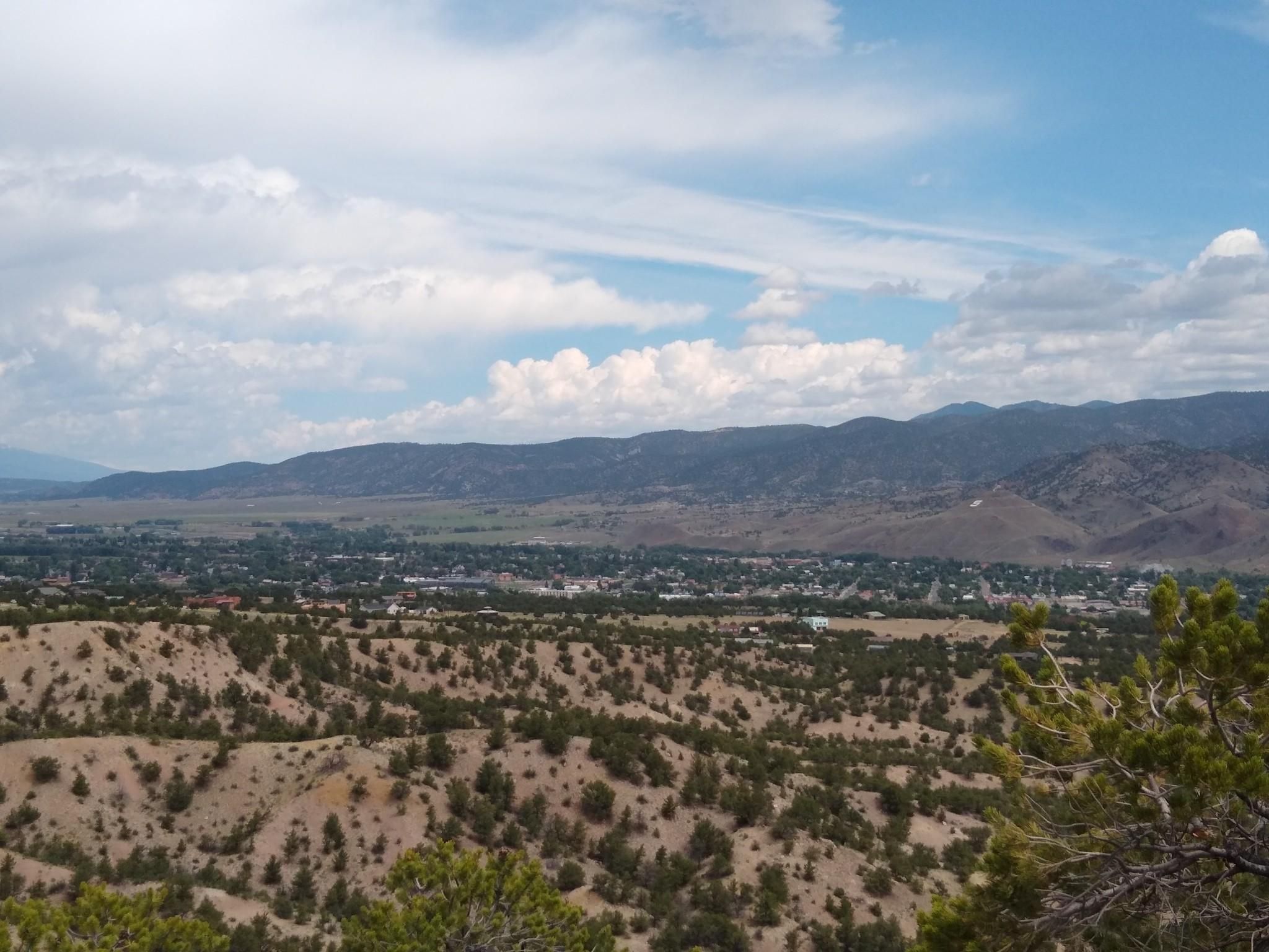 Daytime view of a town in a valley, arid hills, and distant mountains. - Racetrack and Lost Trails loop