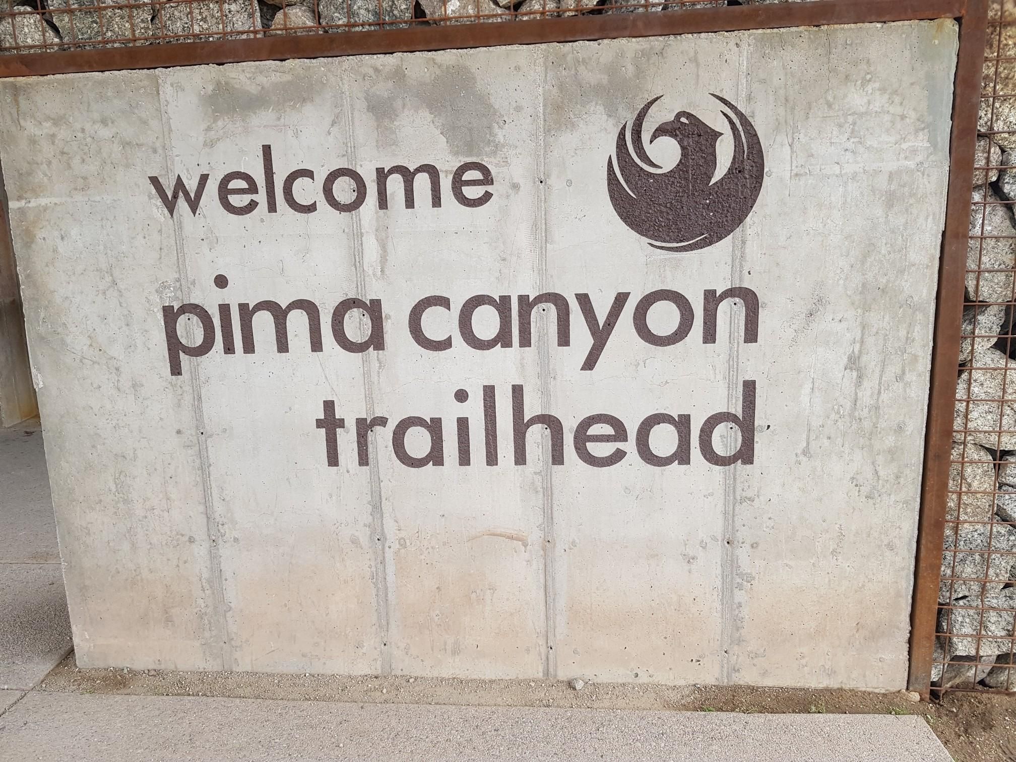 Concrete sign with 'welcome pima canyon trailhead' and a bird logo. - Javelina Canyon and Ridgeline Loop Trail